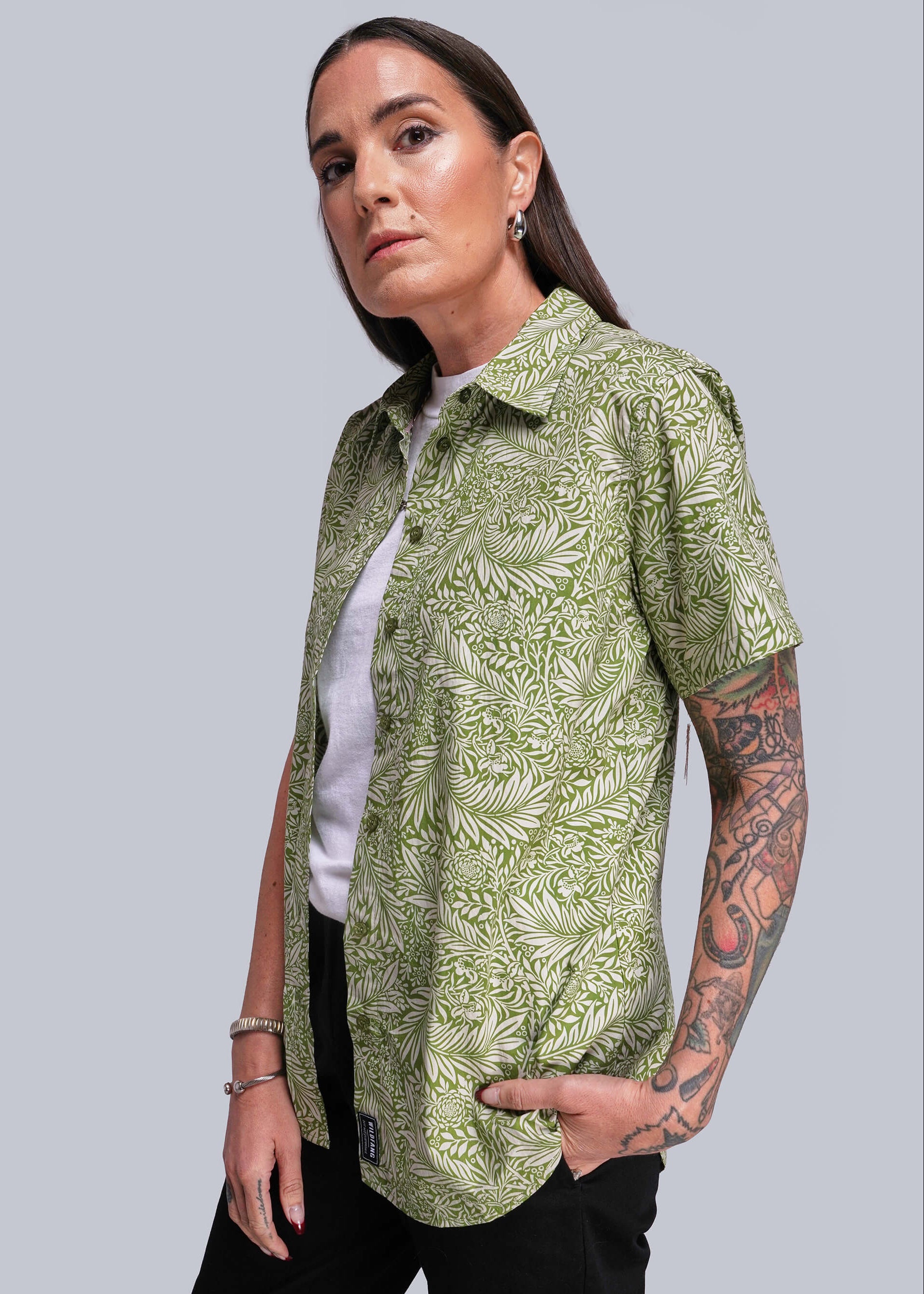 S=Person wearing a green patterned shirt against a gray background