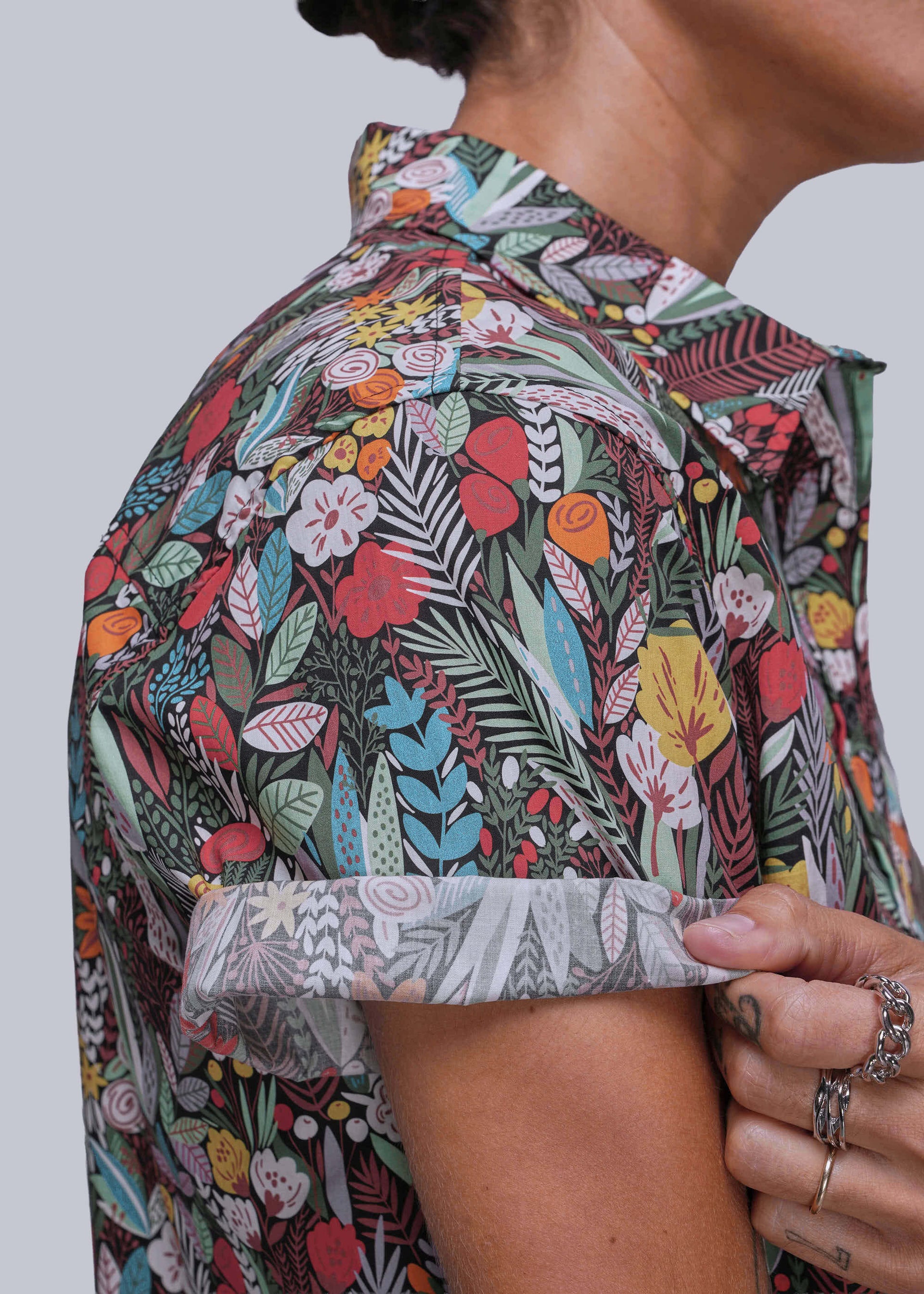 S=Person wearing a colorful floral patterned shirt against a plain background