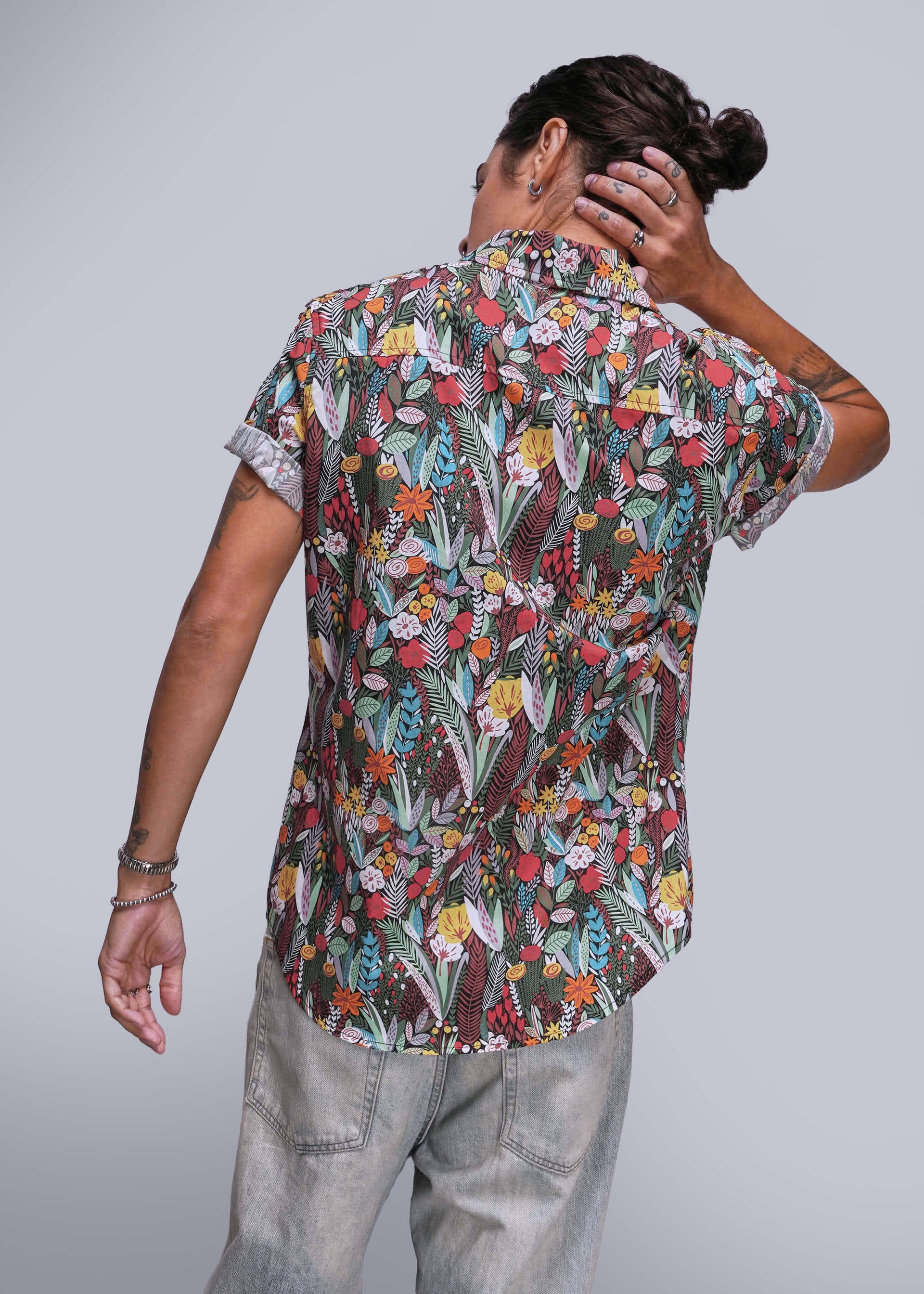 S=Person wearing a colorful floral shirt with their back to the camera on a light gray background