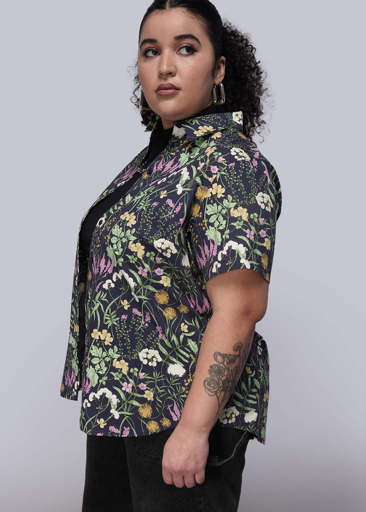 1X=Person wearing a floral shirt and black shorts on a plain background