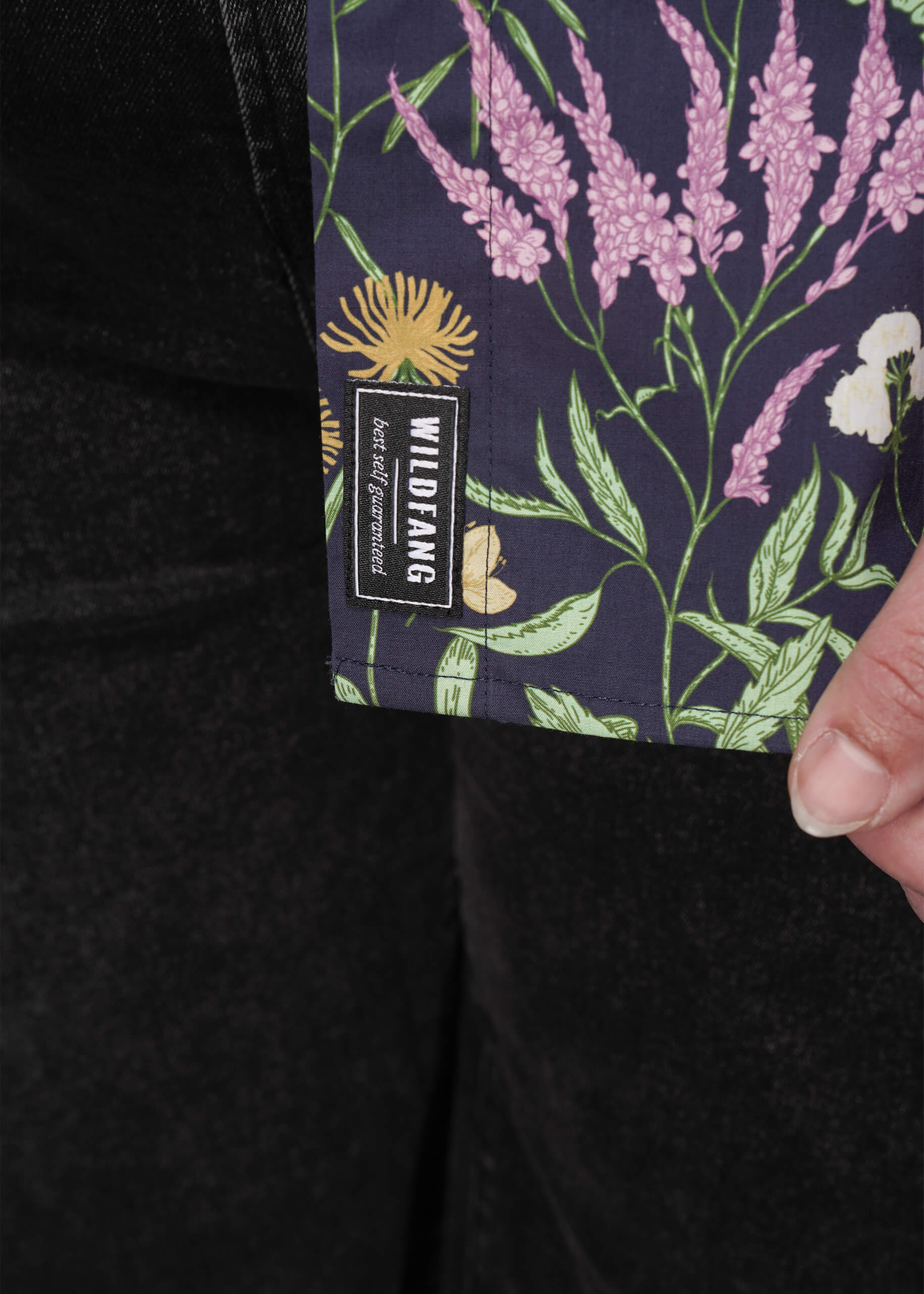 1X=Close-up of a floral-patterned fabric with a visible brand label on a dark background.