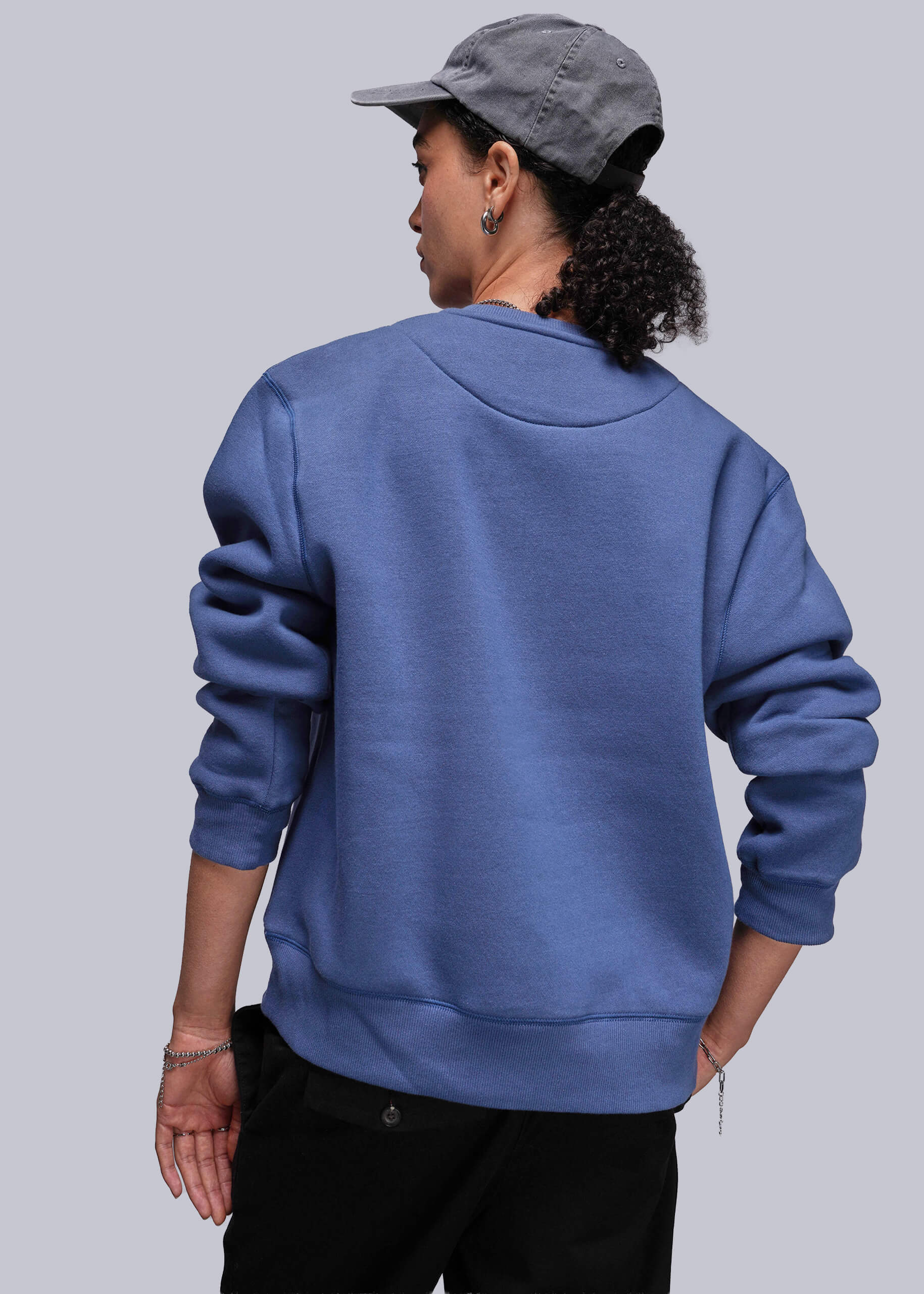 S=Person wearing a blue sweatshirt and gray cap on a plain background