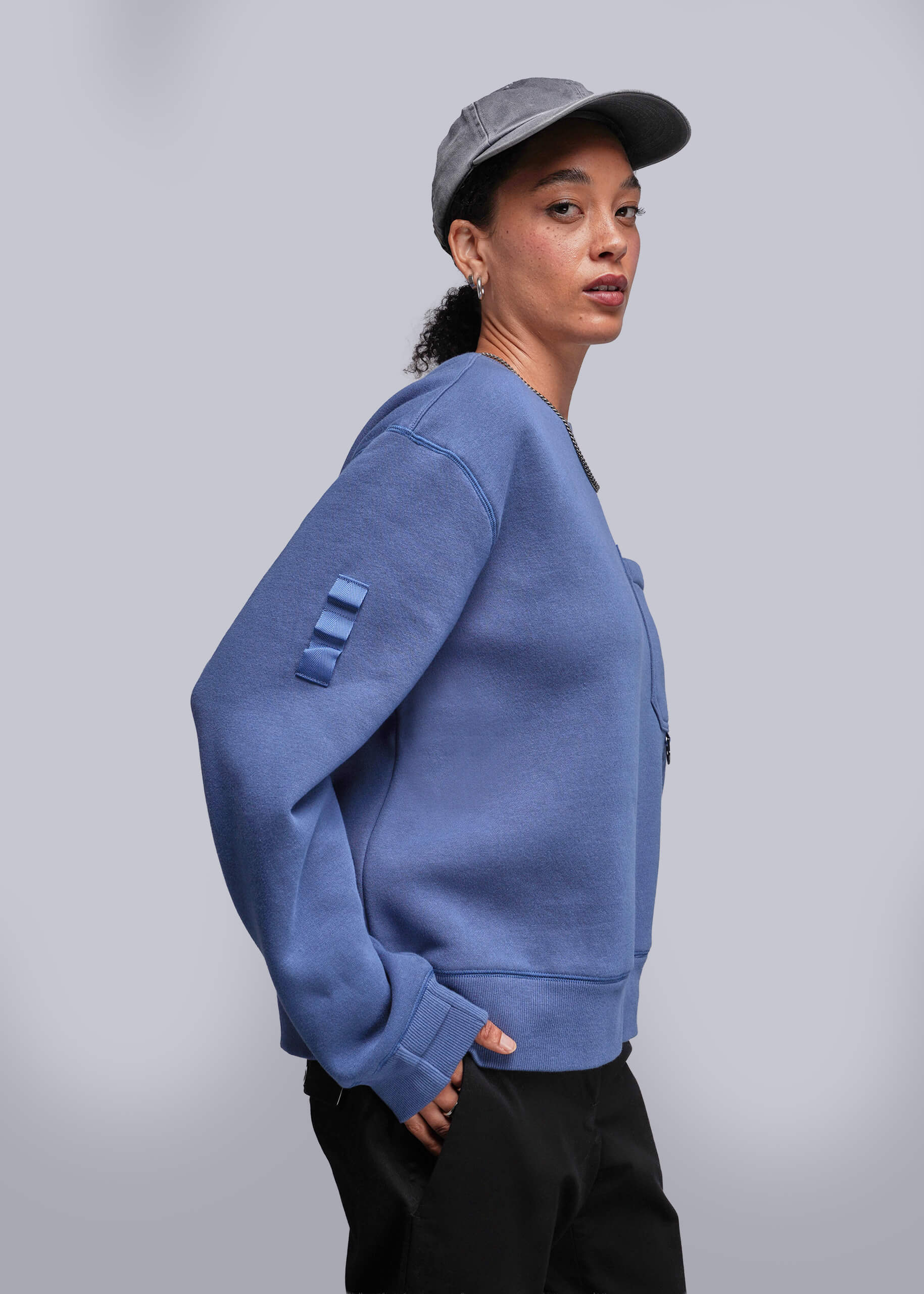 S=Person wearing a blue sweatshirt with a gray cap on a plain background