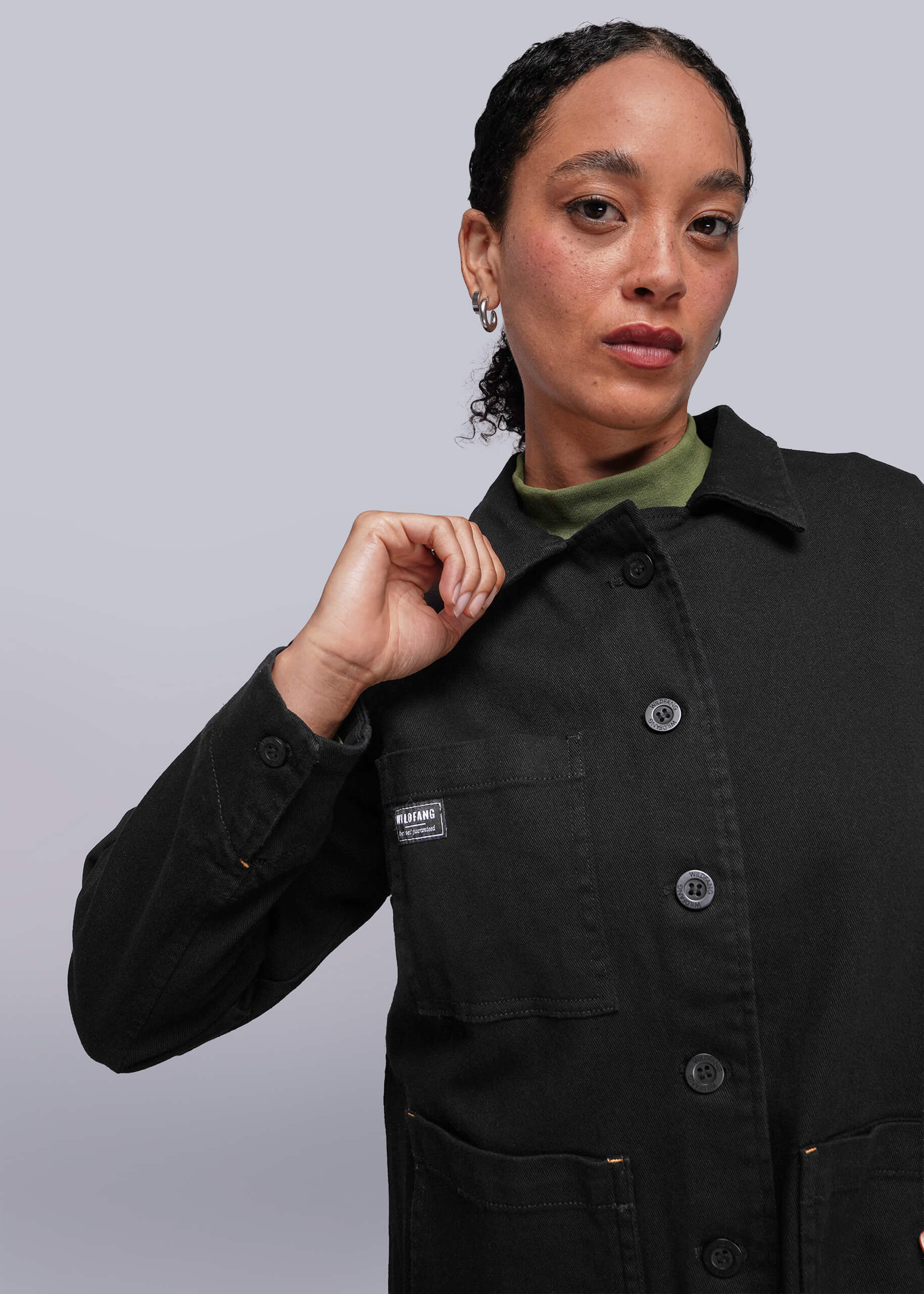 S=Person wearing a black jacket with a brand logo on a light gray background