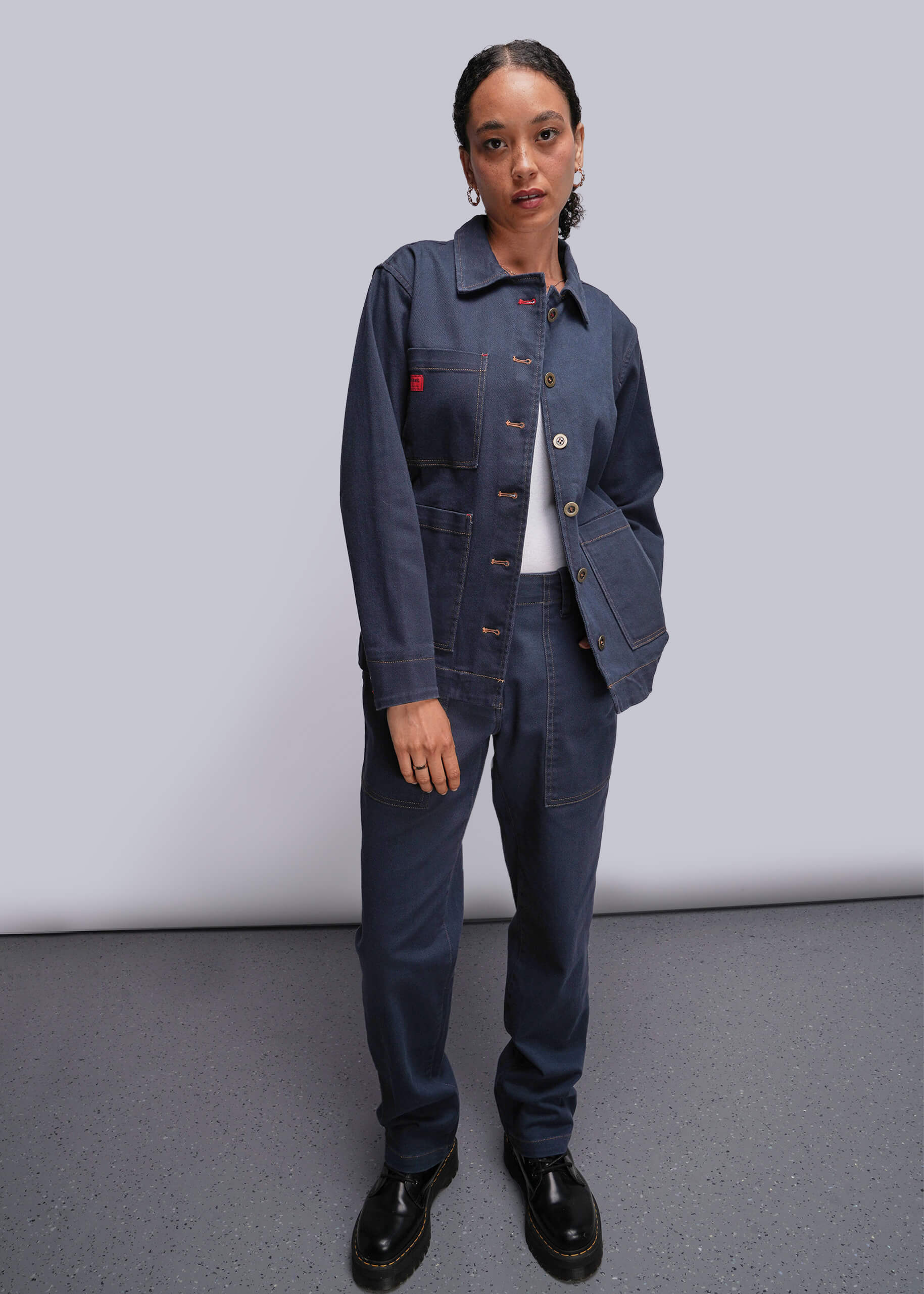 S=Person wearing a blue denim jacket and pants against a plain background