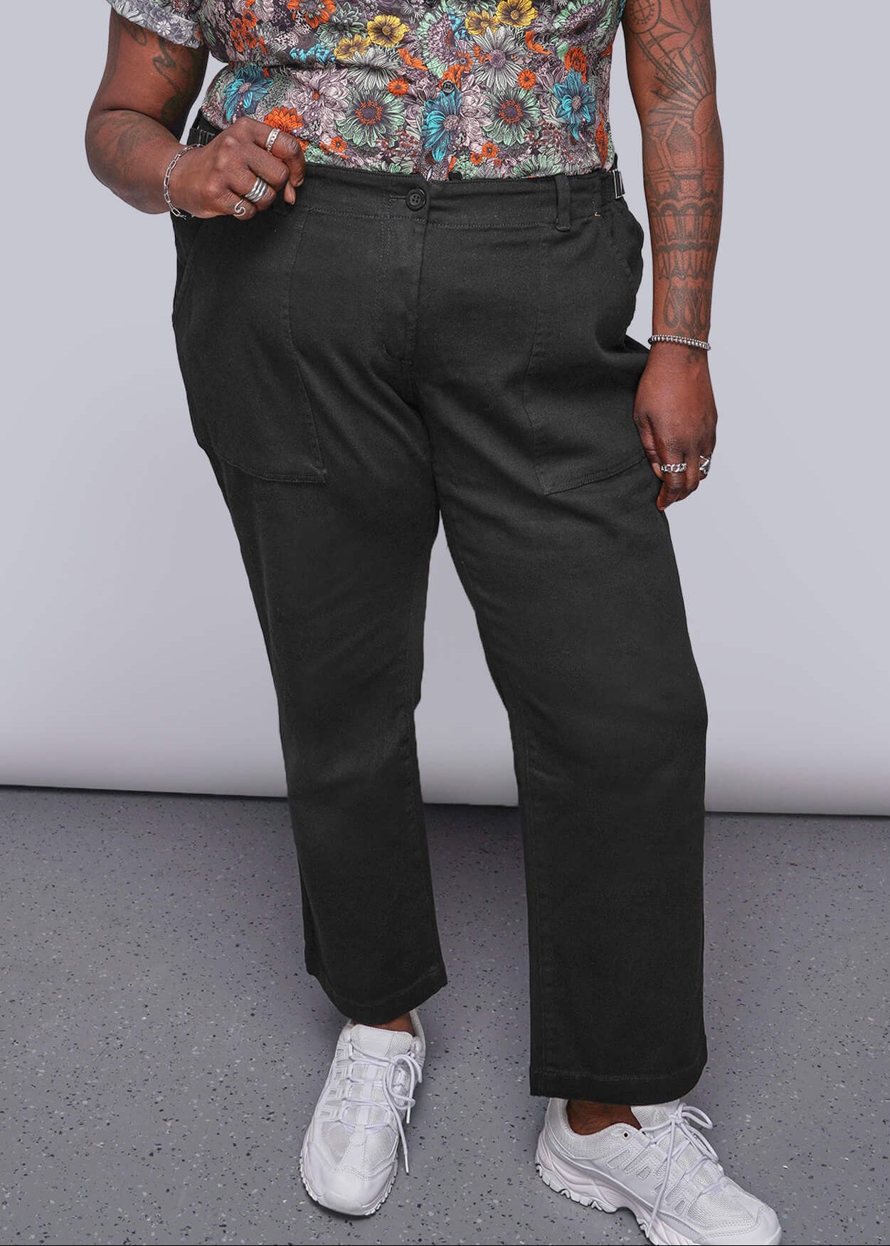 1X=Person wearing a colorful floral shirt and black pants against a plain background