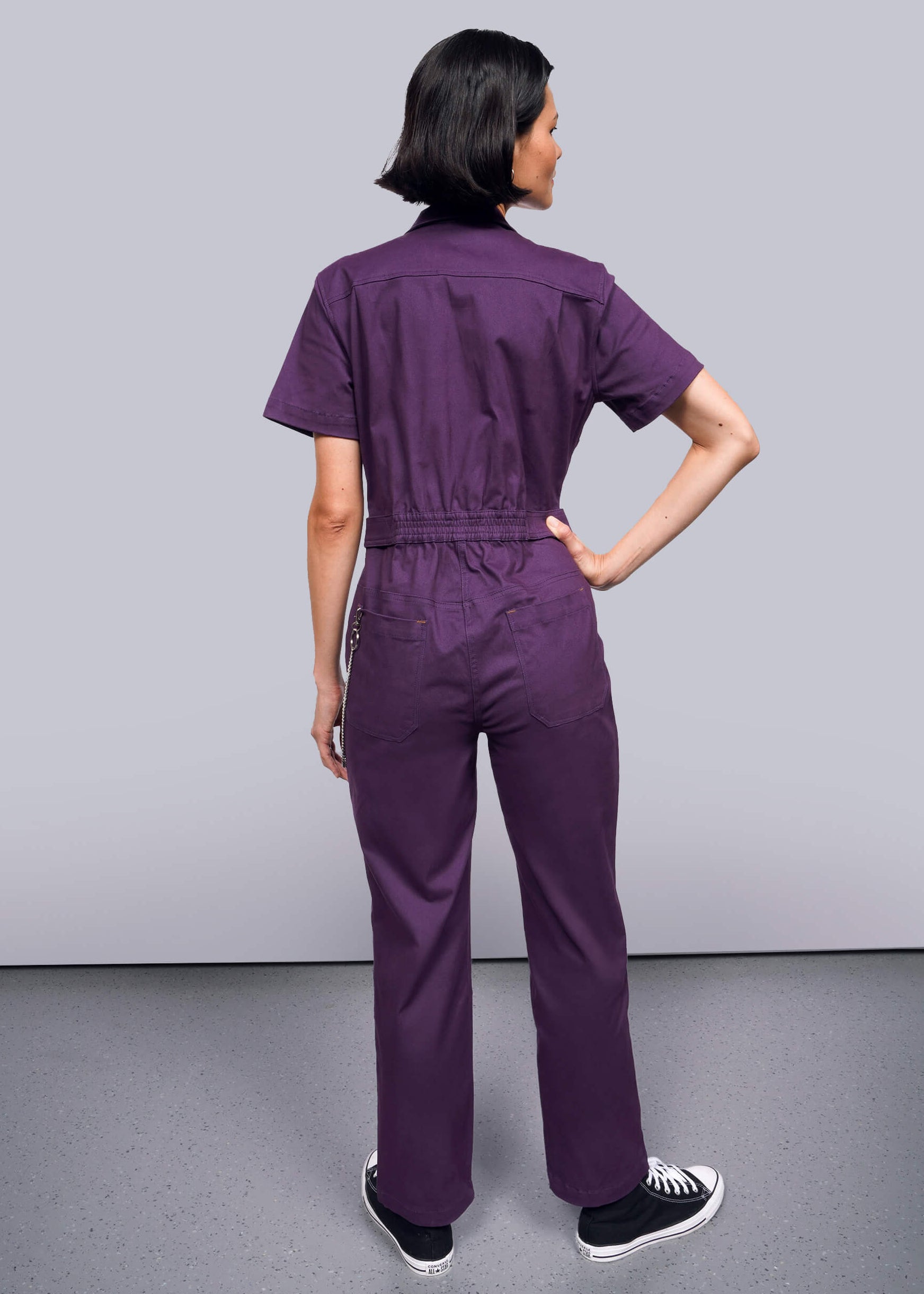 S=Person wearing a purple jumpsuit against a plain background