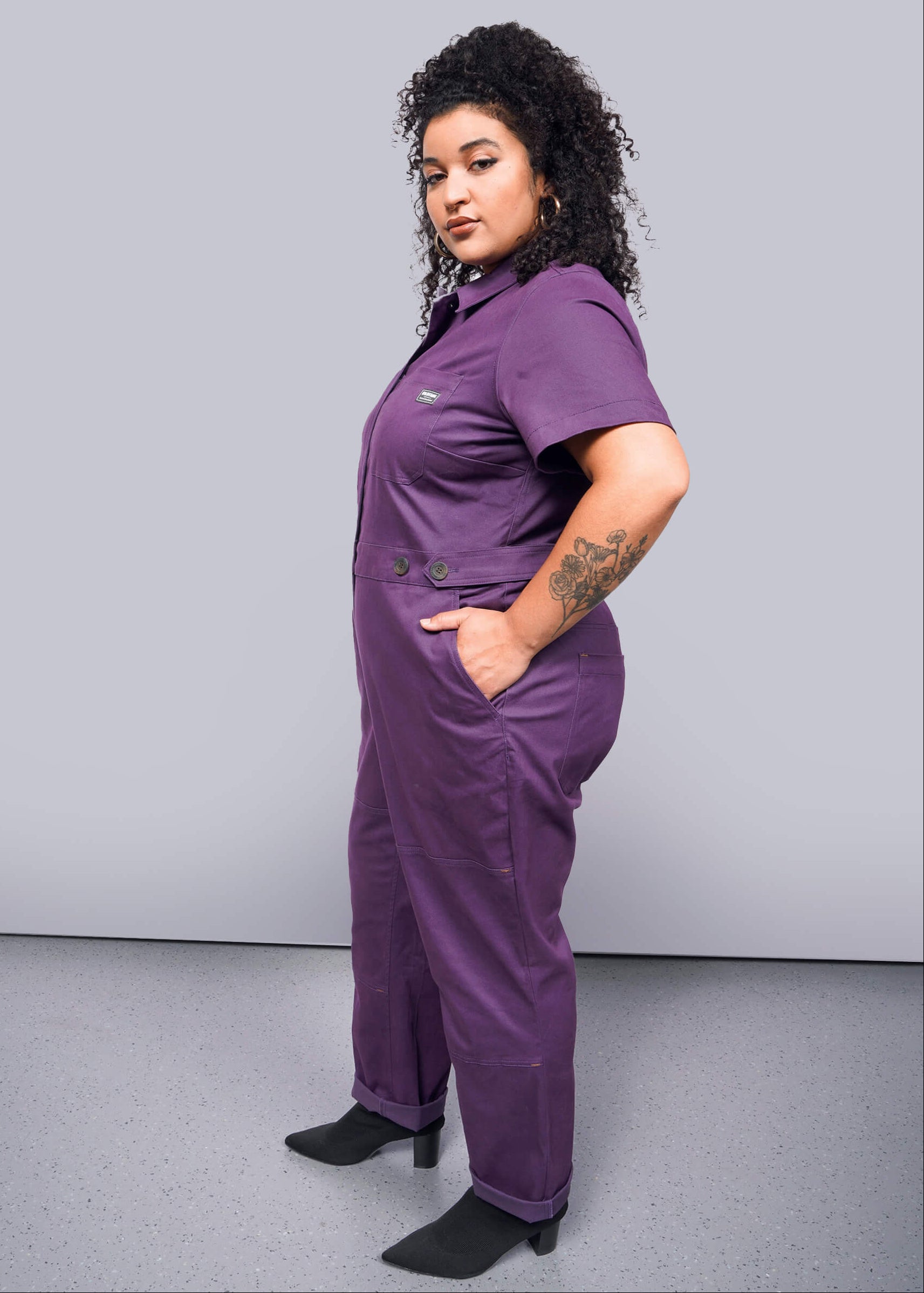 1X=Person wearing a purple jumpsuit against a plain background