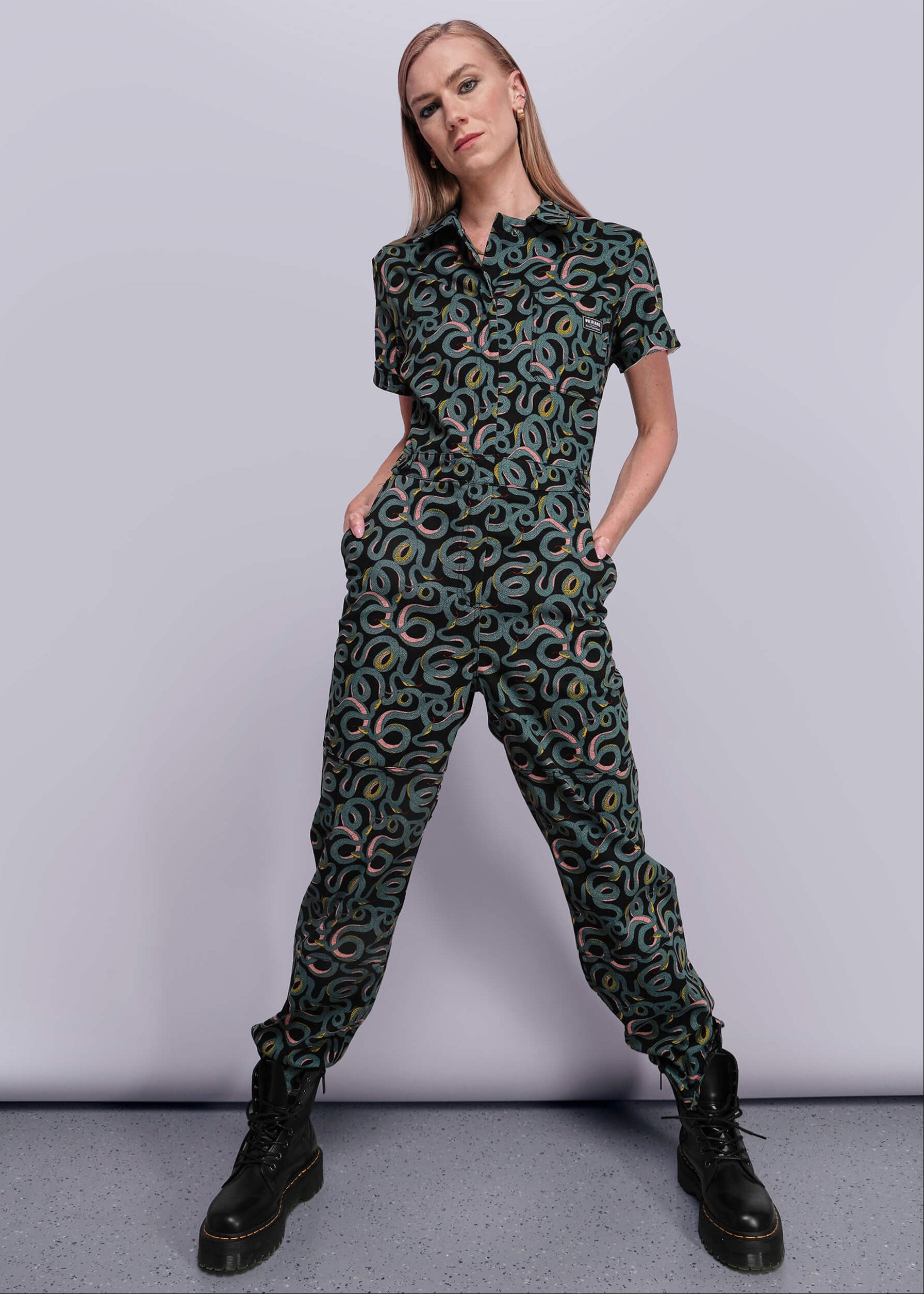 Person wearing a patterned jumpsuit on a plain background