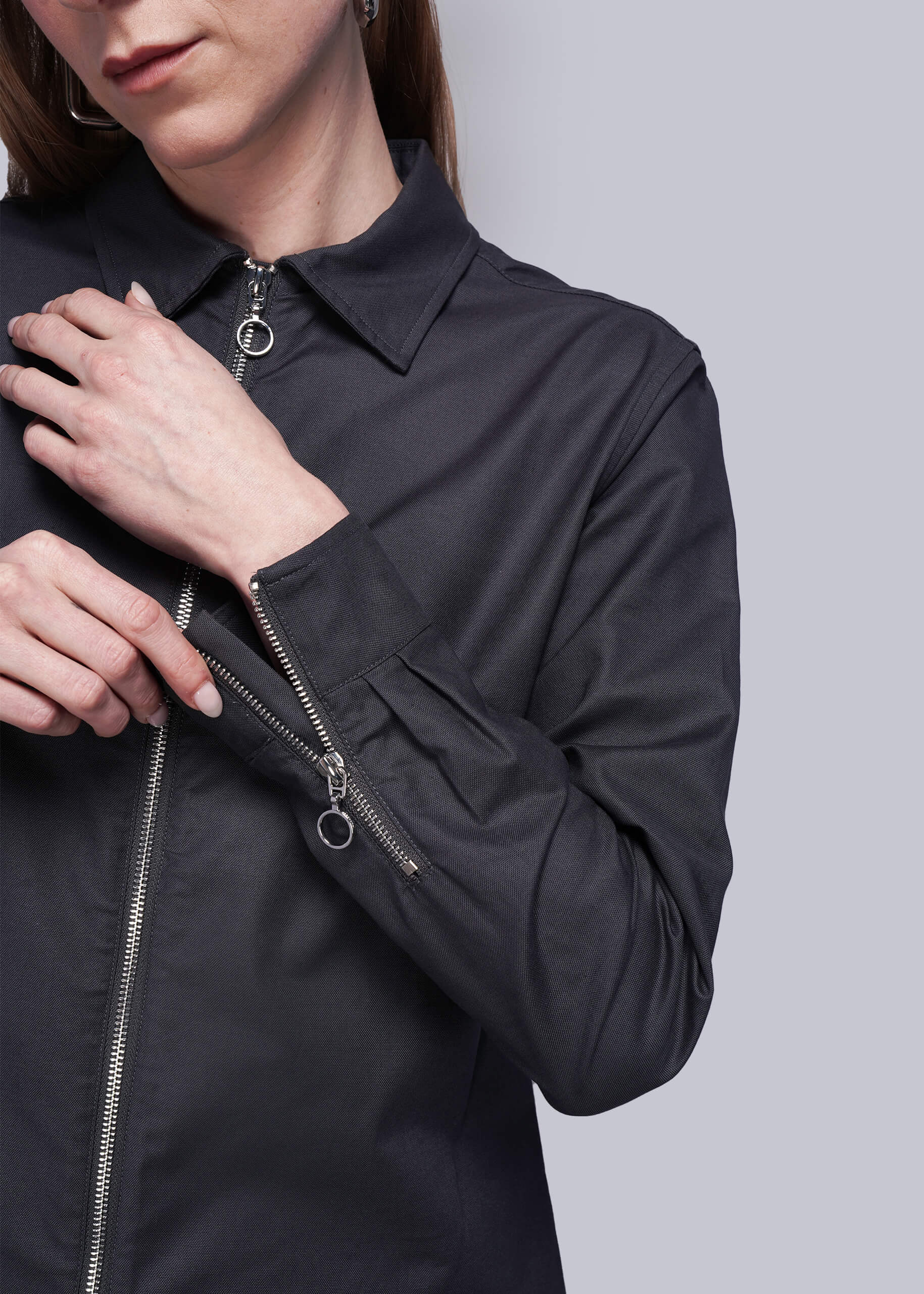 S=Close up of person wearing a black zip up shirt showing zipper detail on cuffs