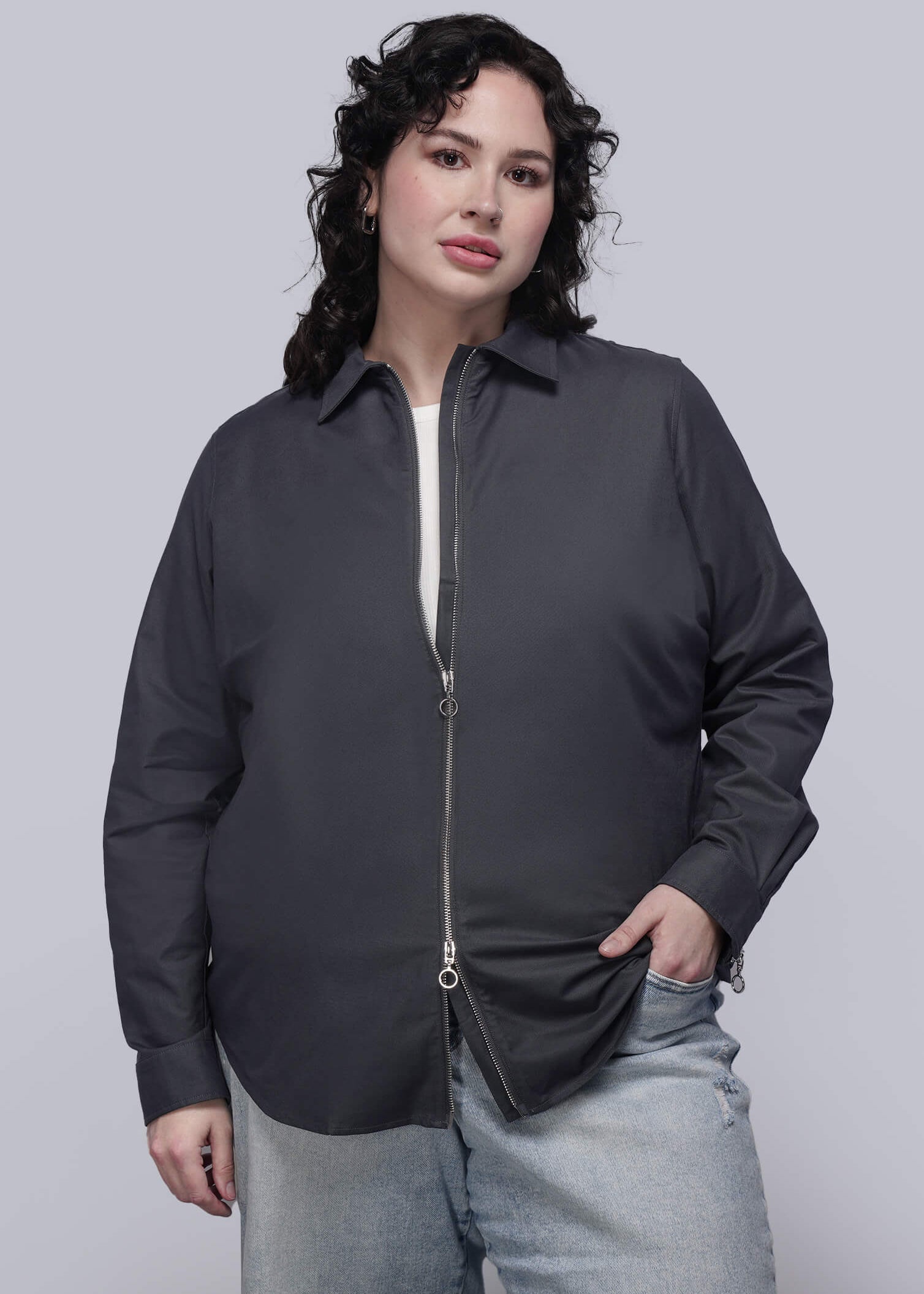 1X=Person wearing a black zip up shirt and light blue jeans on a plain background