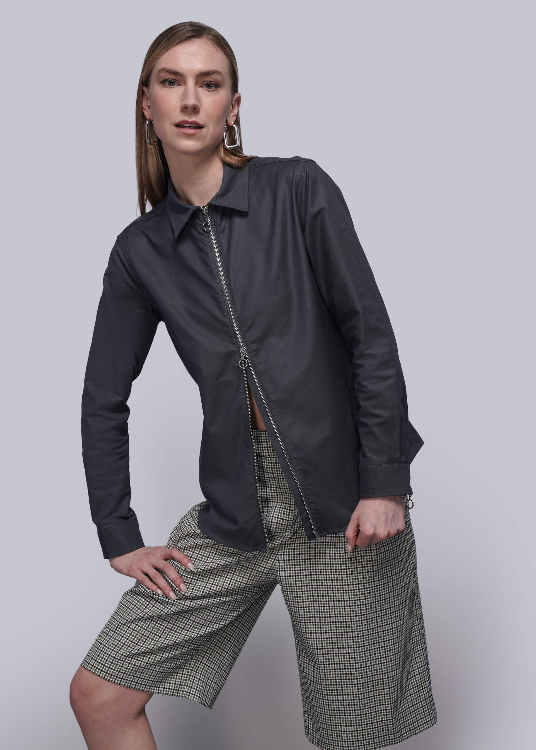 S=Person wearing a black zip up shirt, checkered shorts, and black boots on a plain background