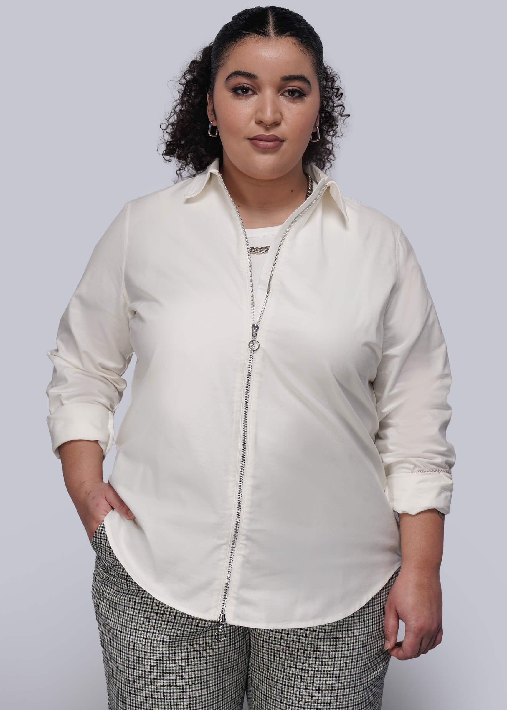 1X=Person wearing a white shirt with zipper and plaid pants on a plain background