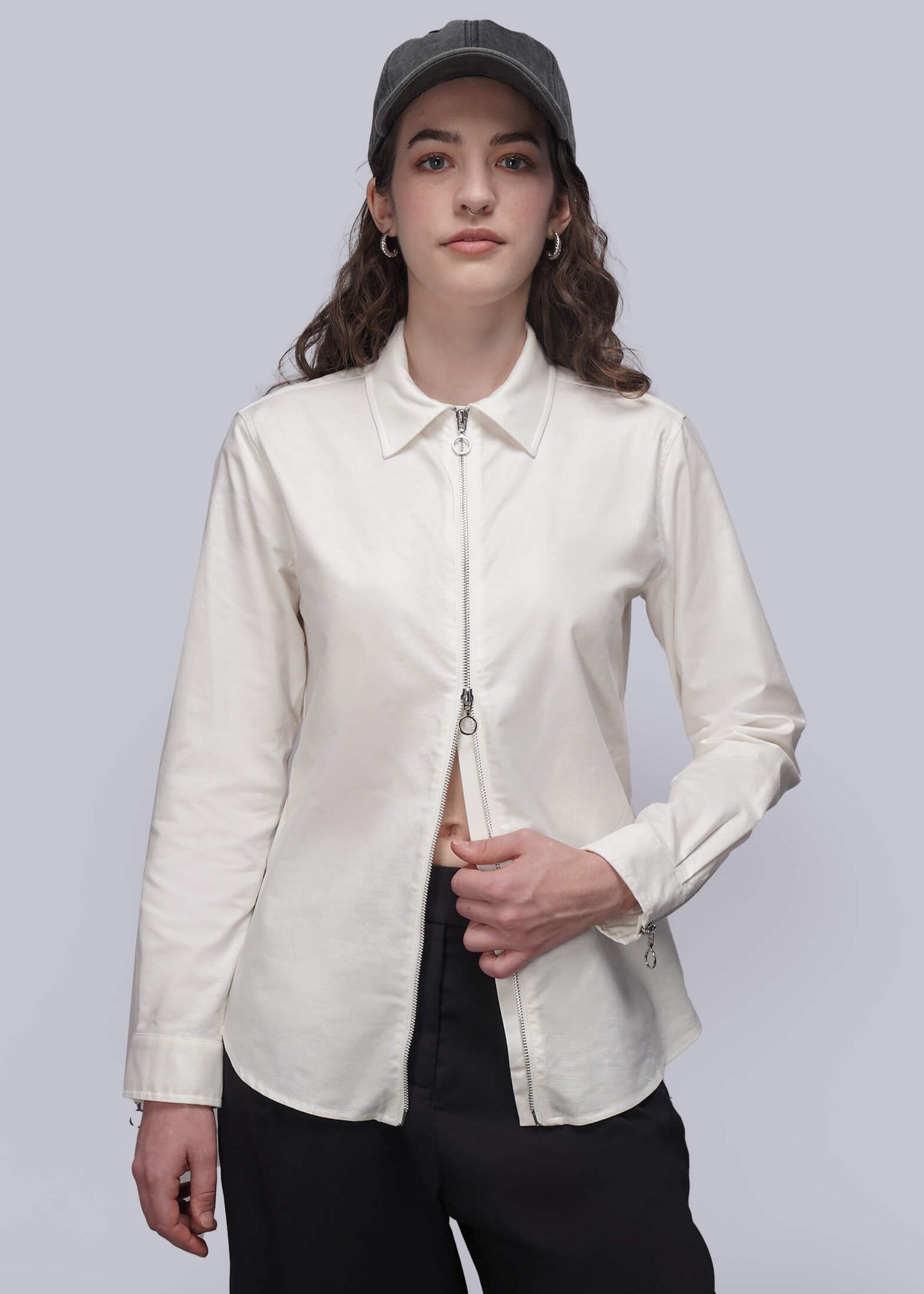 S=Person wearing a white shirt with a zipper and black pants on a plain background