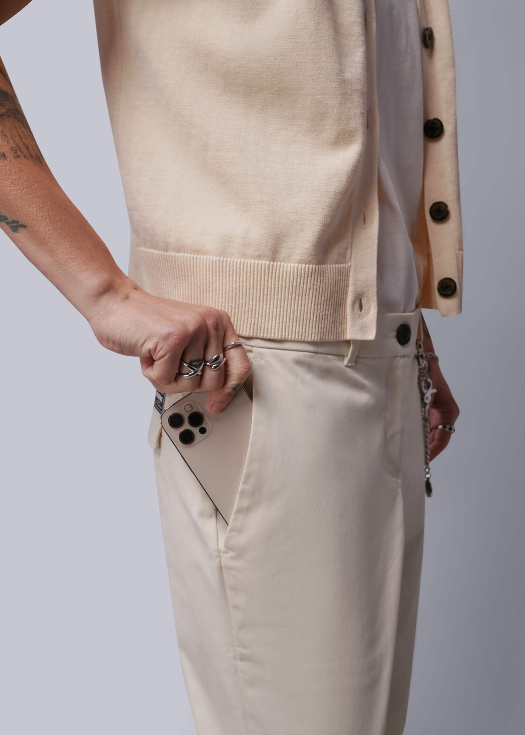 Person wearing a beige vest and pants with a plain background