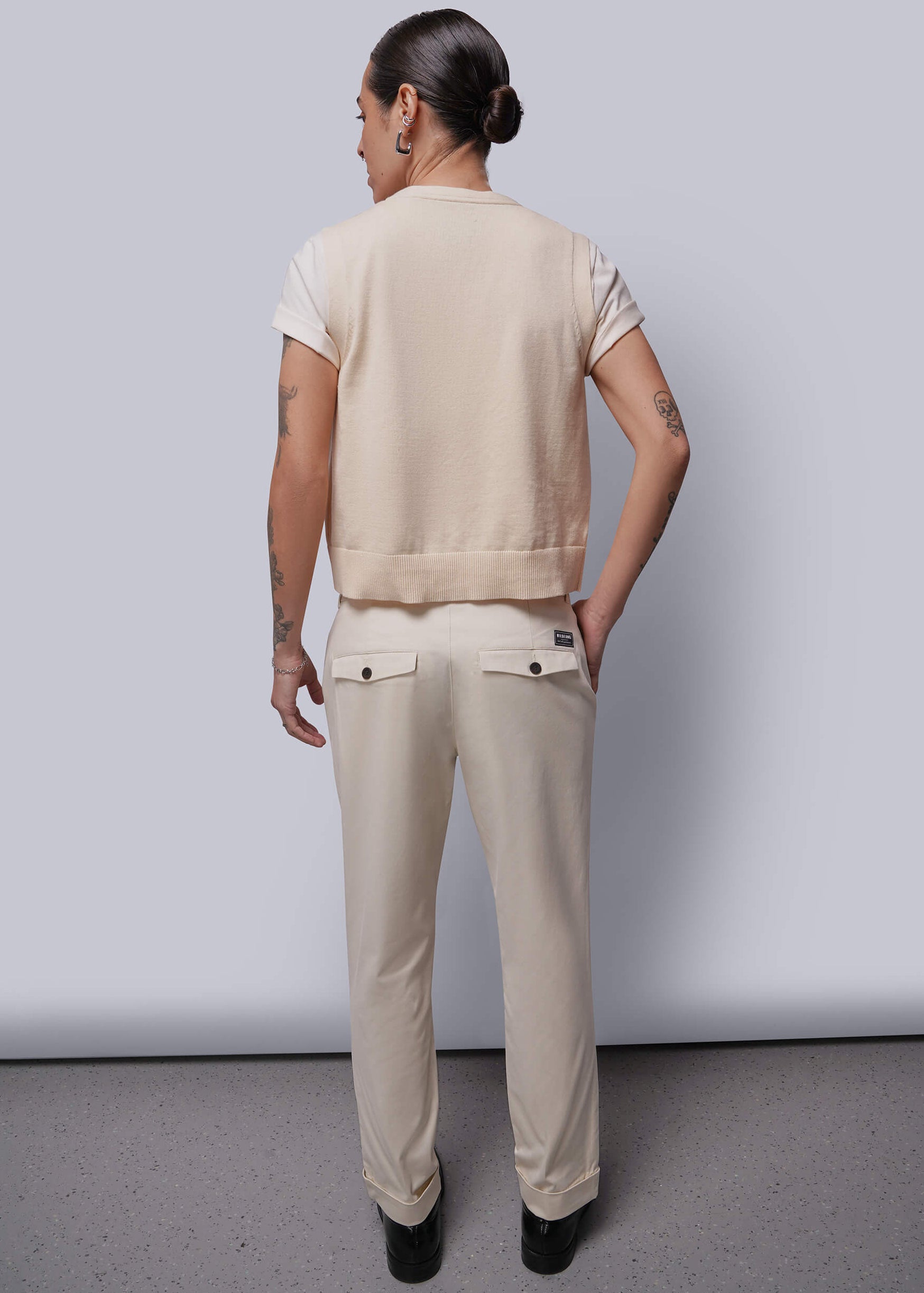 S=Person wearing a beige vest and pants standing against a plain background