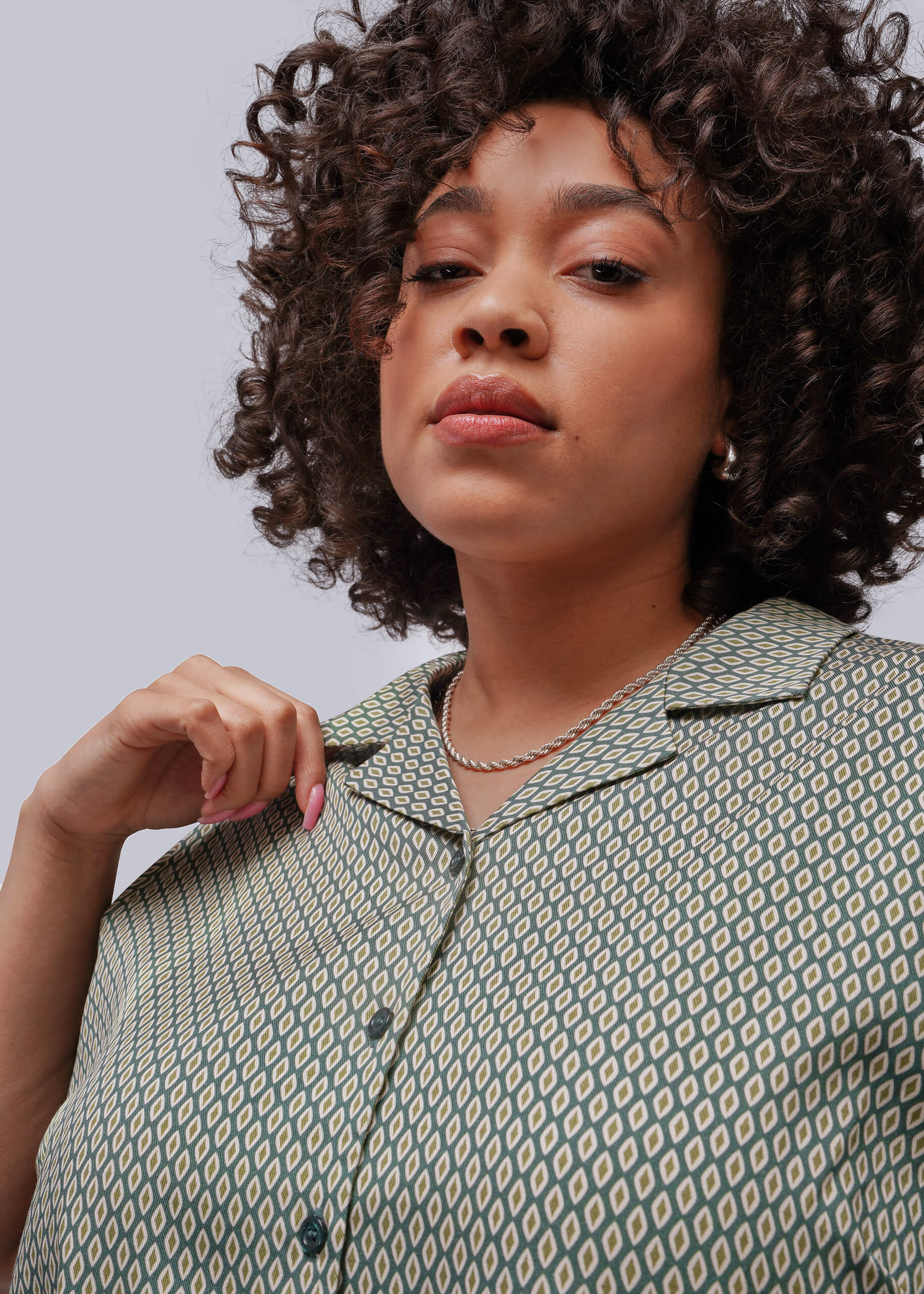 1X=Woman wearing a patterned shirt against a plain background