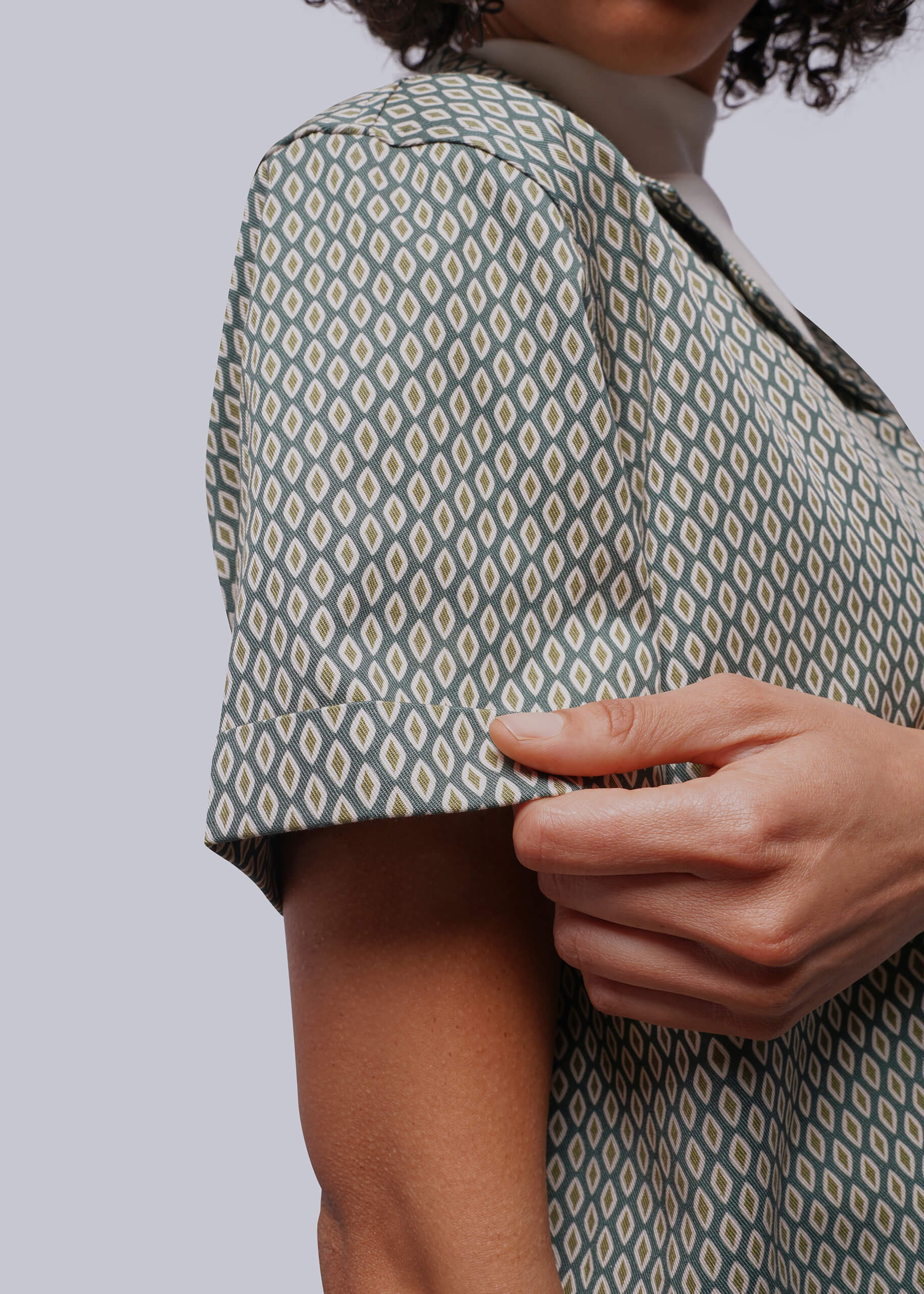 S=Person wearing a patterned shirt with a plain background