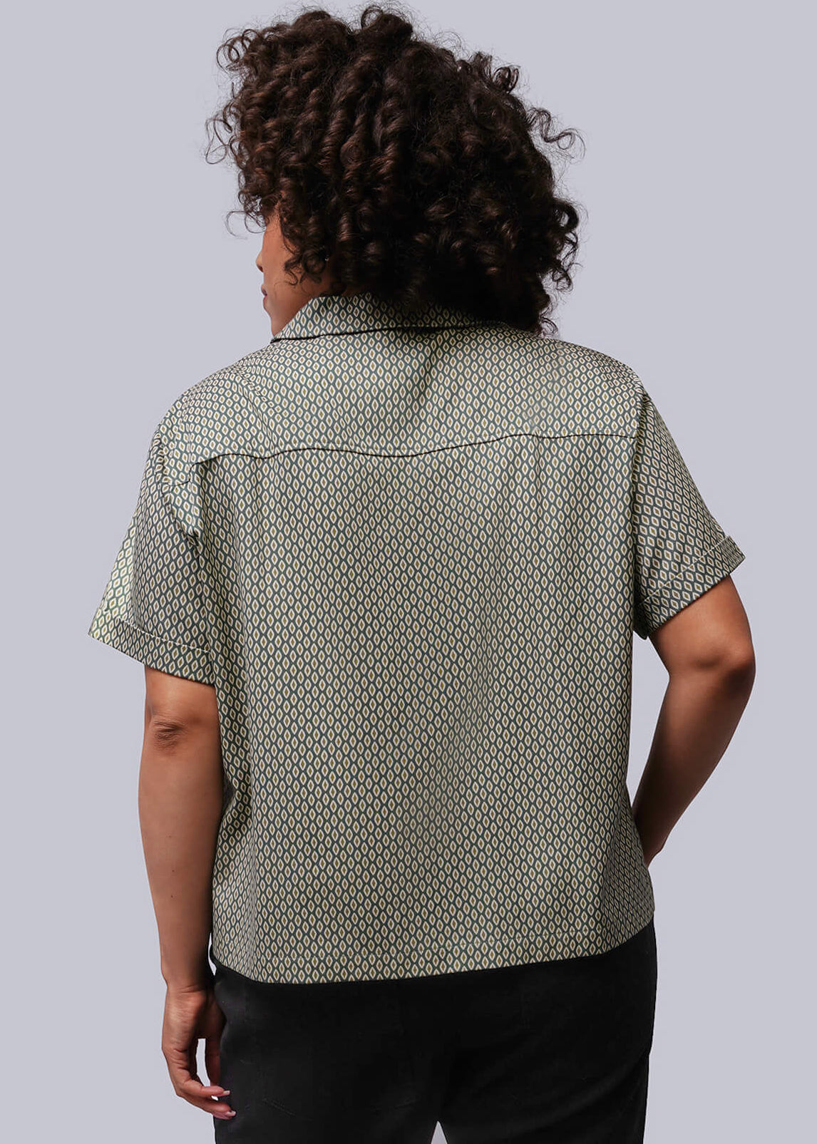 1X=Person wearing a patterned shirt and black pants against a plain background