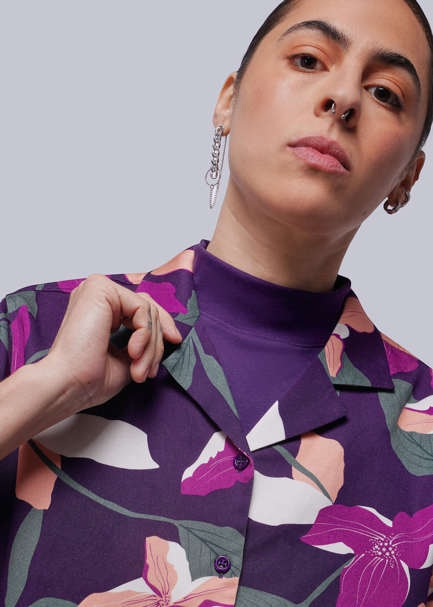 S=Person wearing a purple floral patterned shirt against a plain background