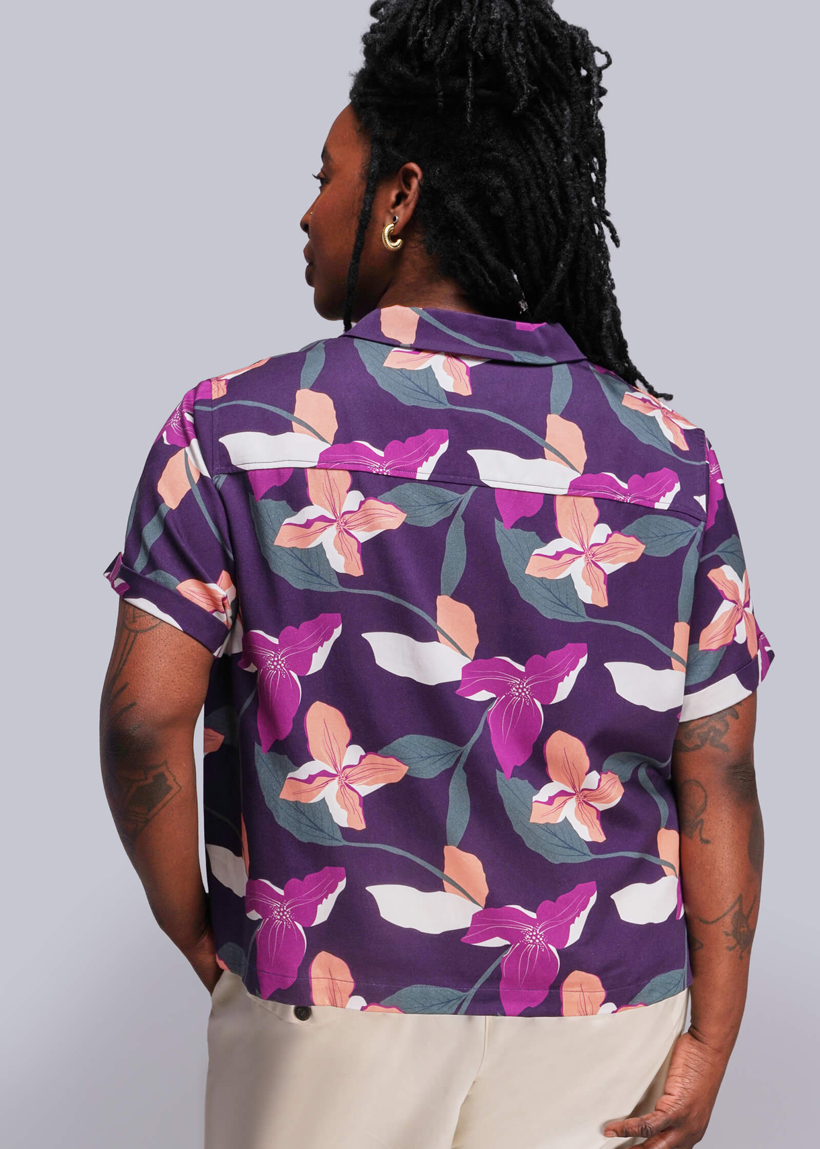 1X=Person wearing a purple floral patterned shirt against a gray background