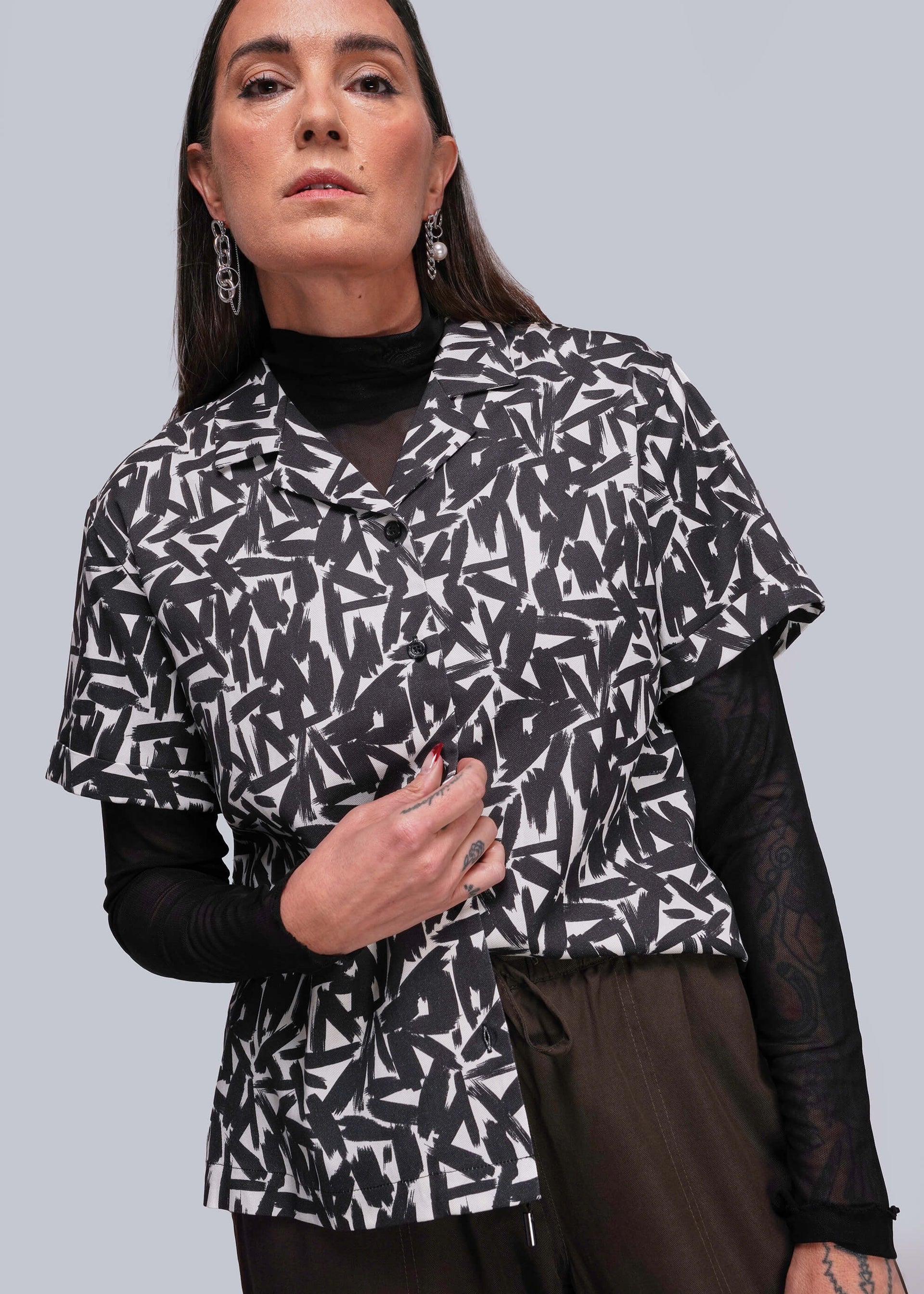 S=Woman wearing a black and white patterned jacket against a gray background