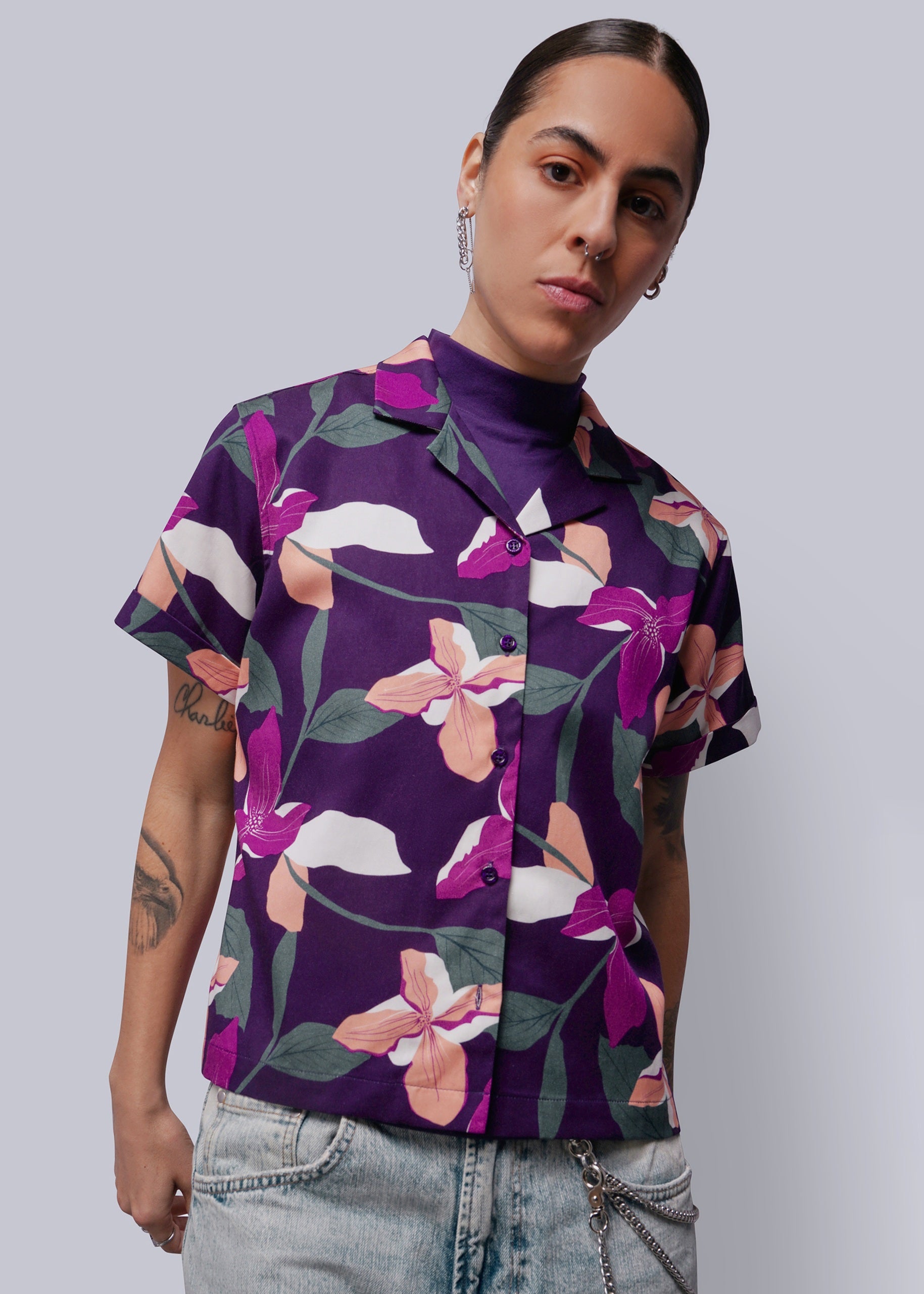 Person wearing a purple floral shirt against a plain background