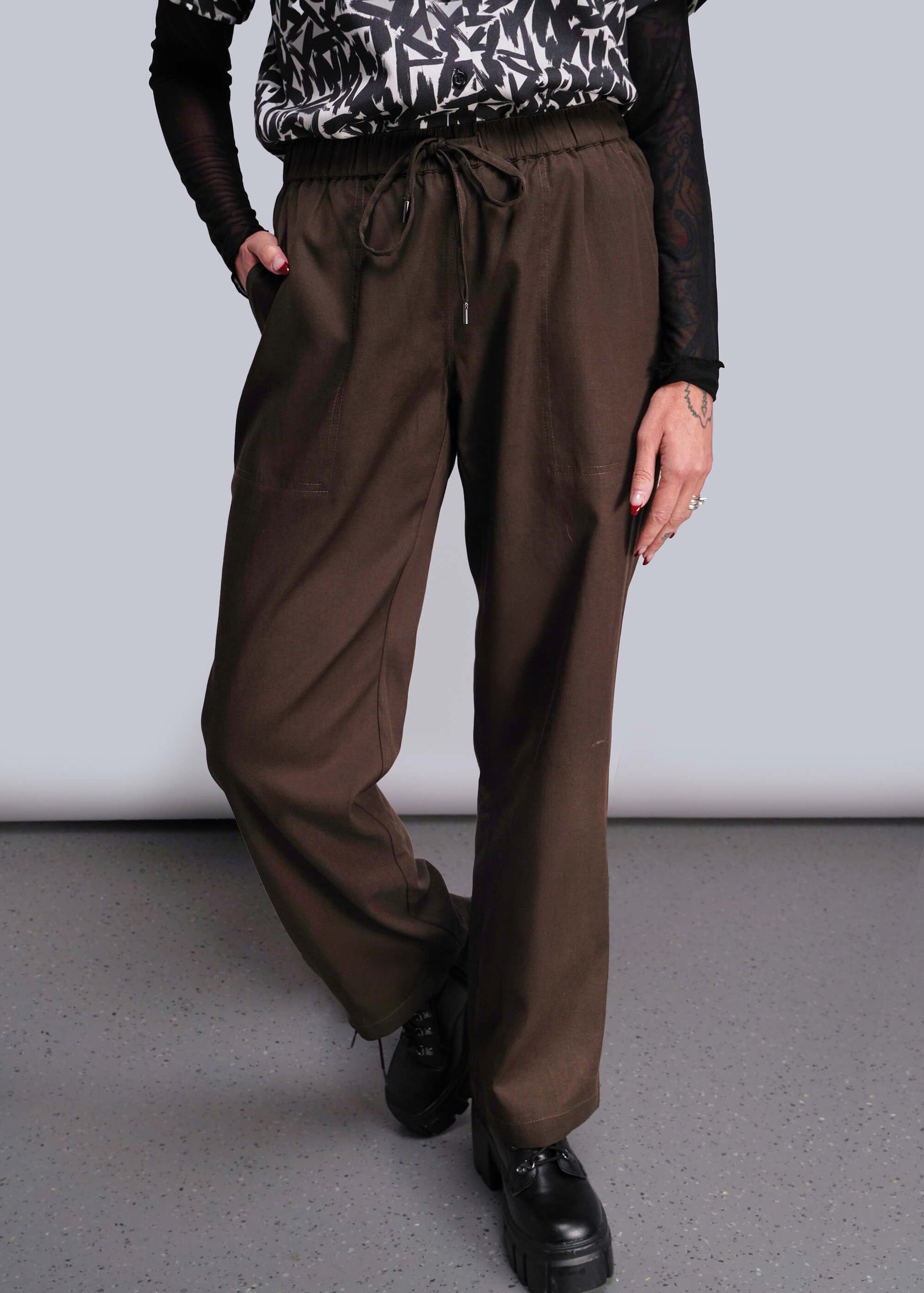 S=Person wearing brown pants and black shoes on a plain background