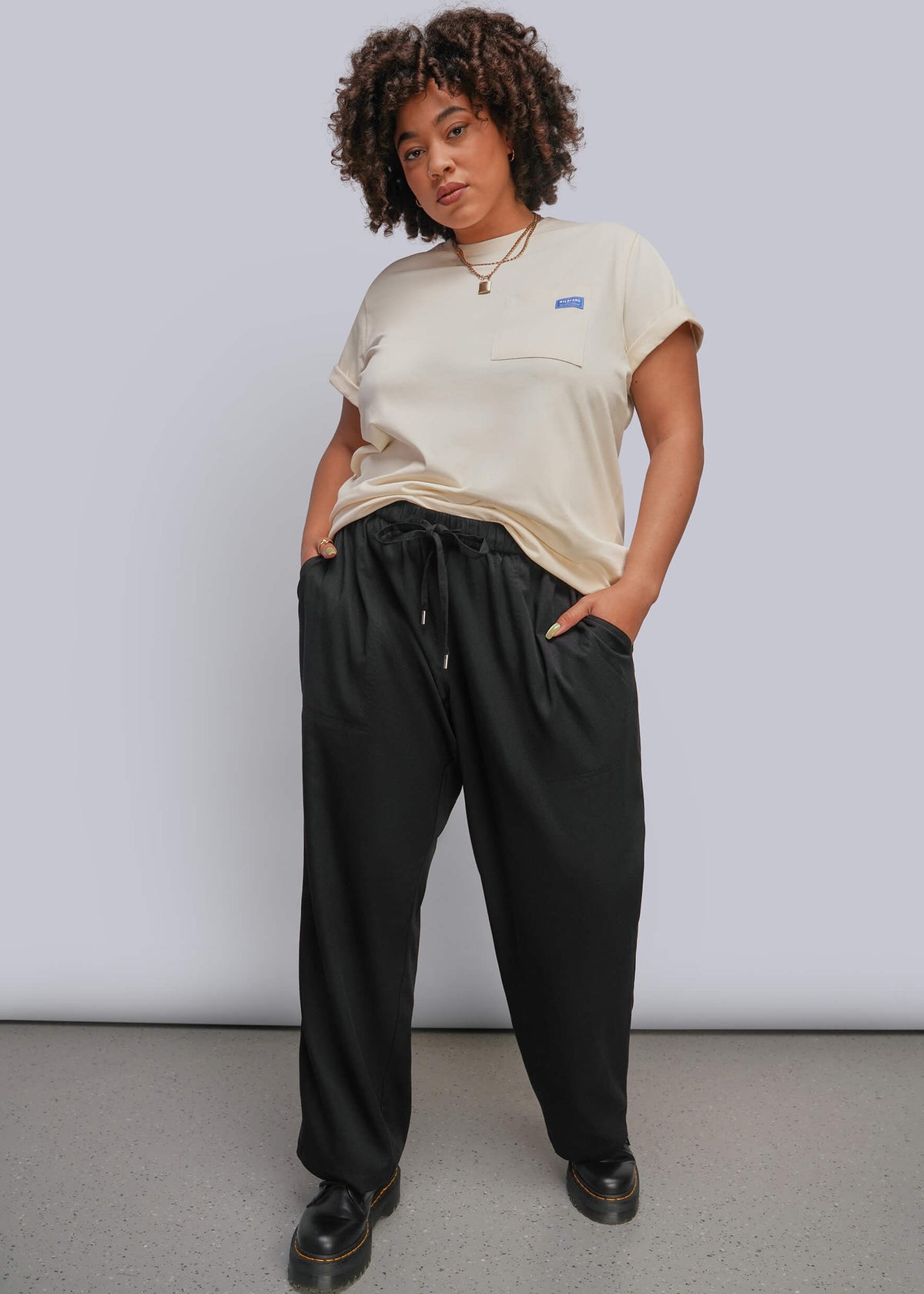 1X=Model wearing off white tshirt with black drawstring pant and black boots
