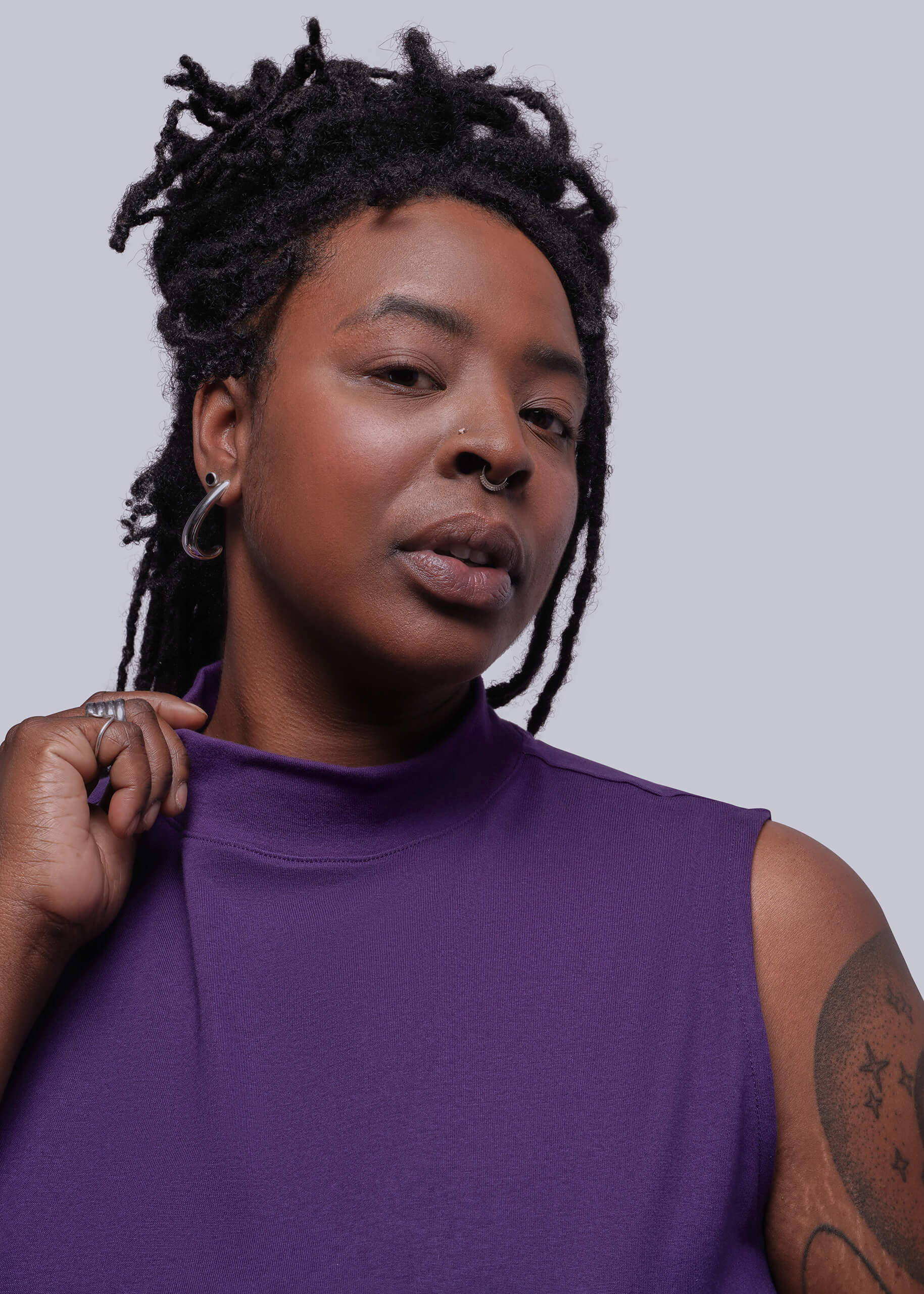 1X=Person wearing a purple sleeveless top against a plain background
