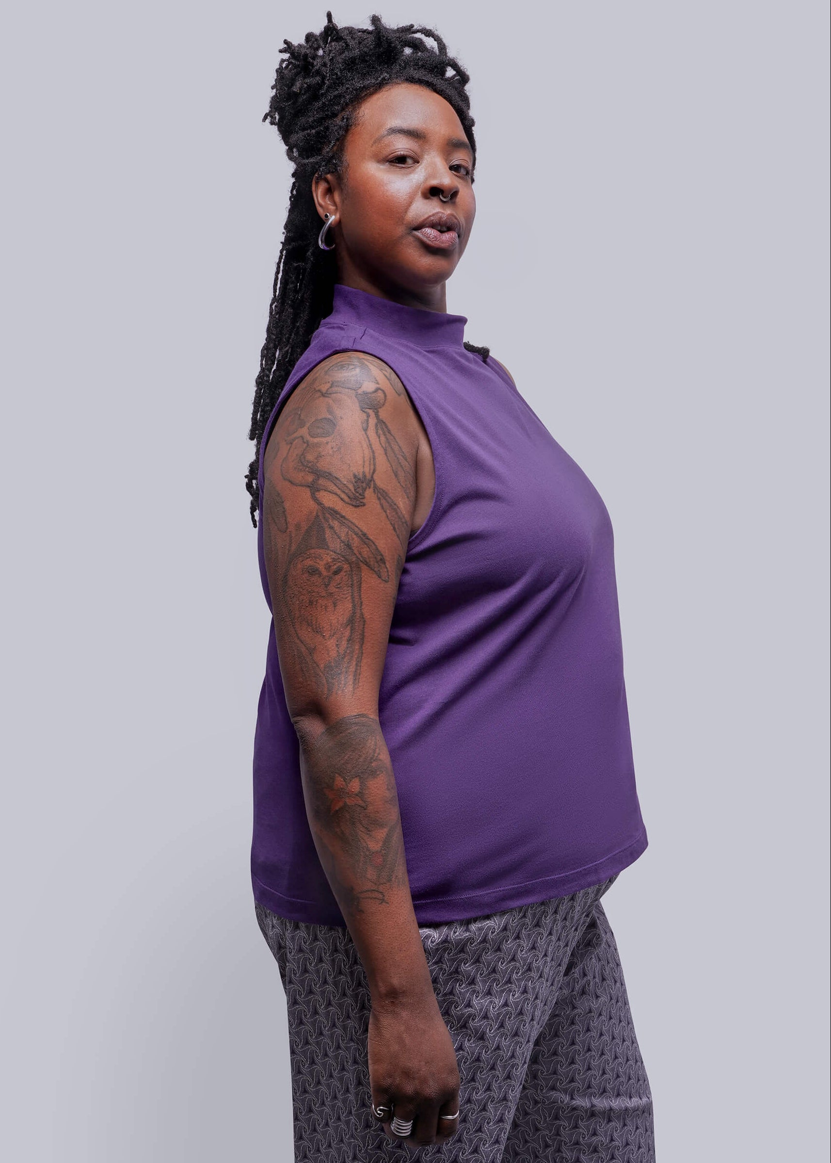 1X=Person wearing a purple sleeveless top against a plain background