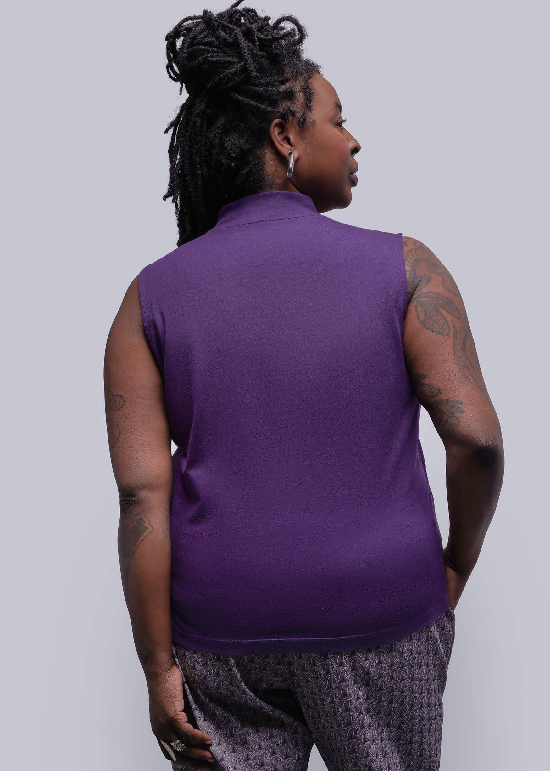 1X=Person wearing a purple sleeveless top against a plain background