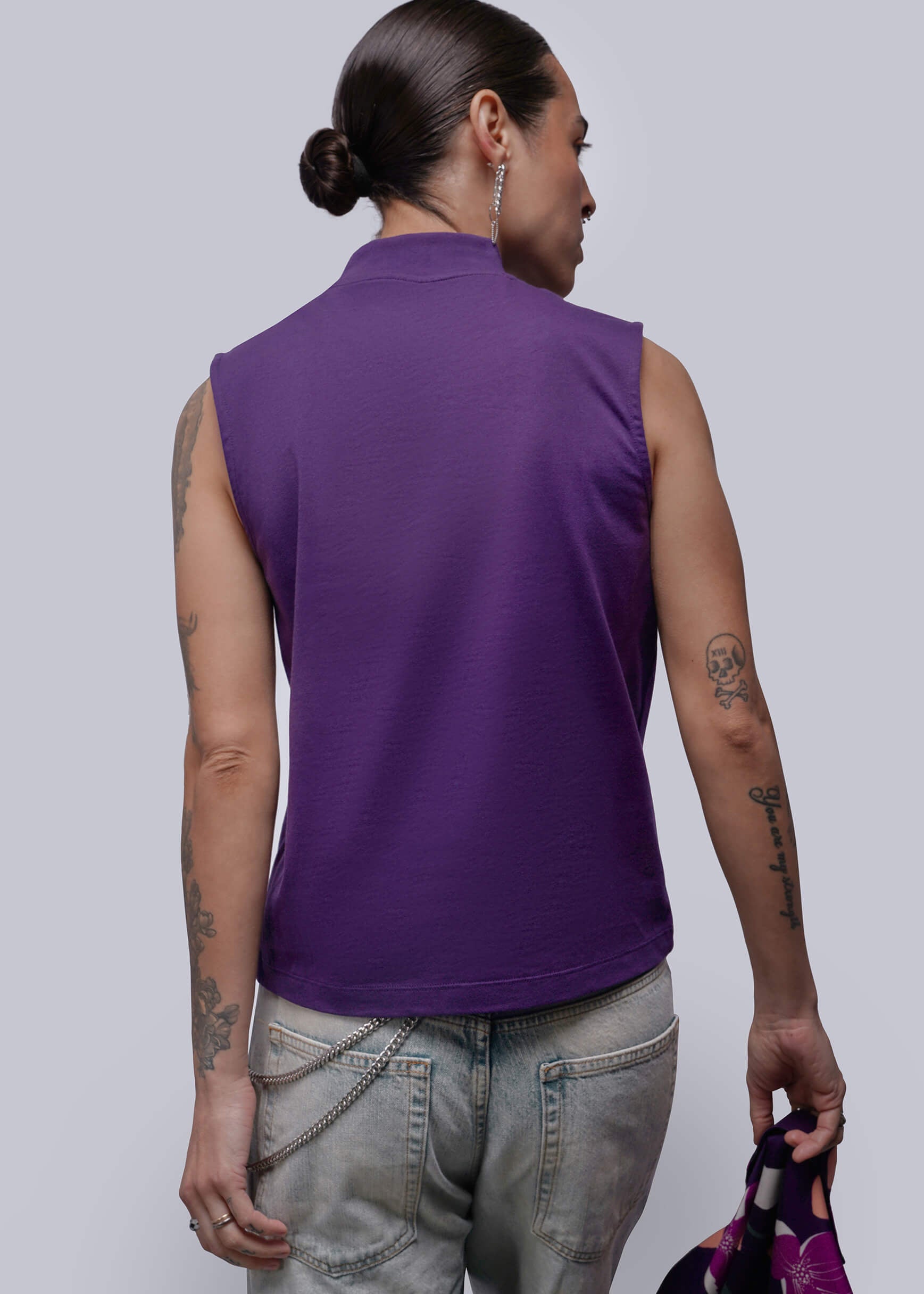 S=Person wearing a purple sleeveless top and gray pants against a plain background