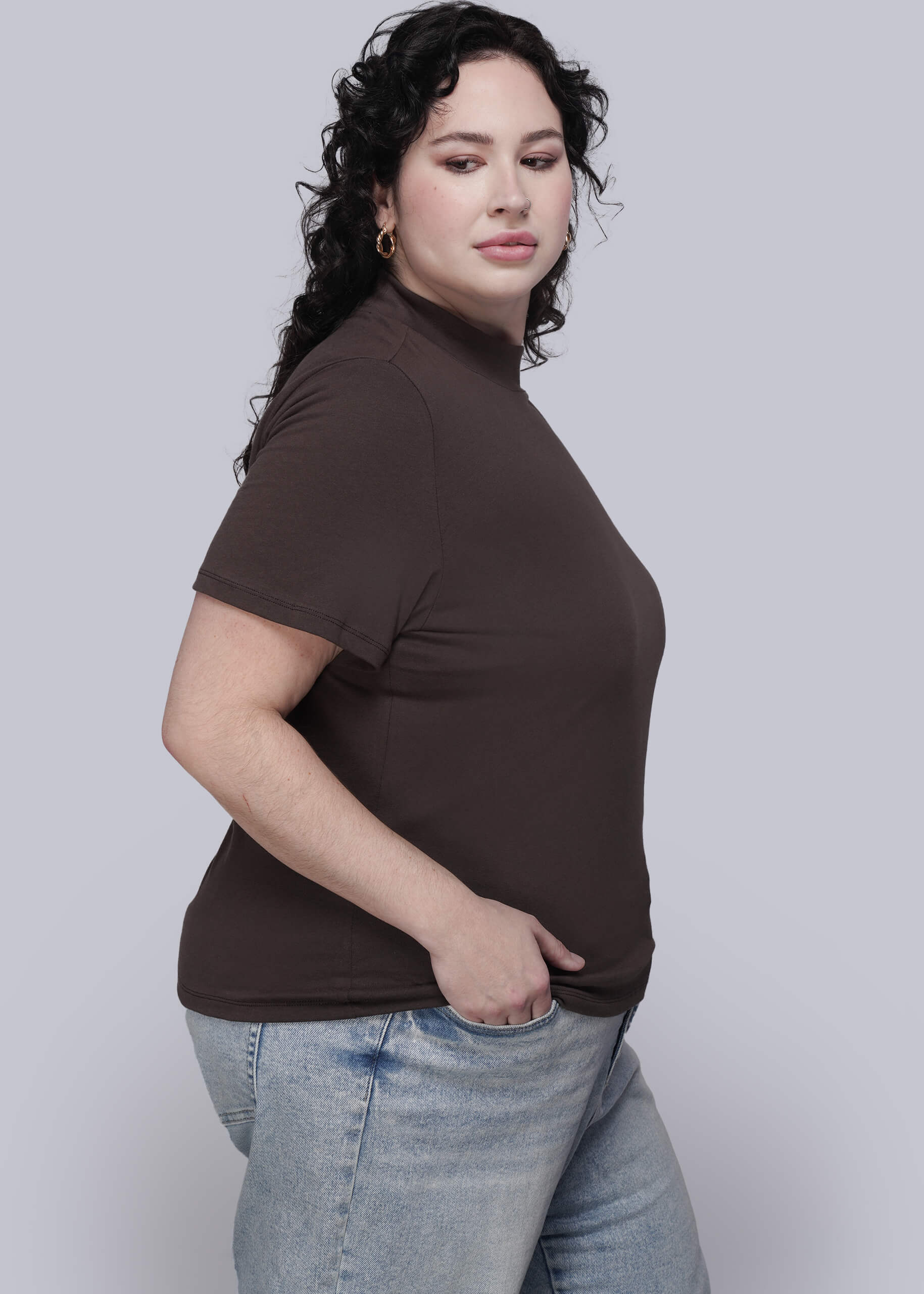 1X=Person wearing a brown mock neck t shirt and light blue jeans against a white background