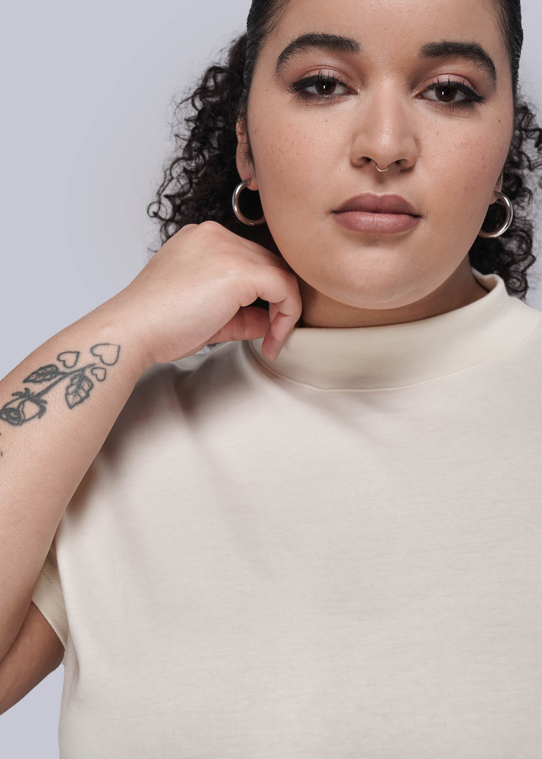 1X=Woman wearing a beige top against a plain background