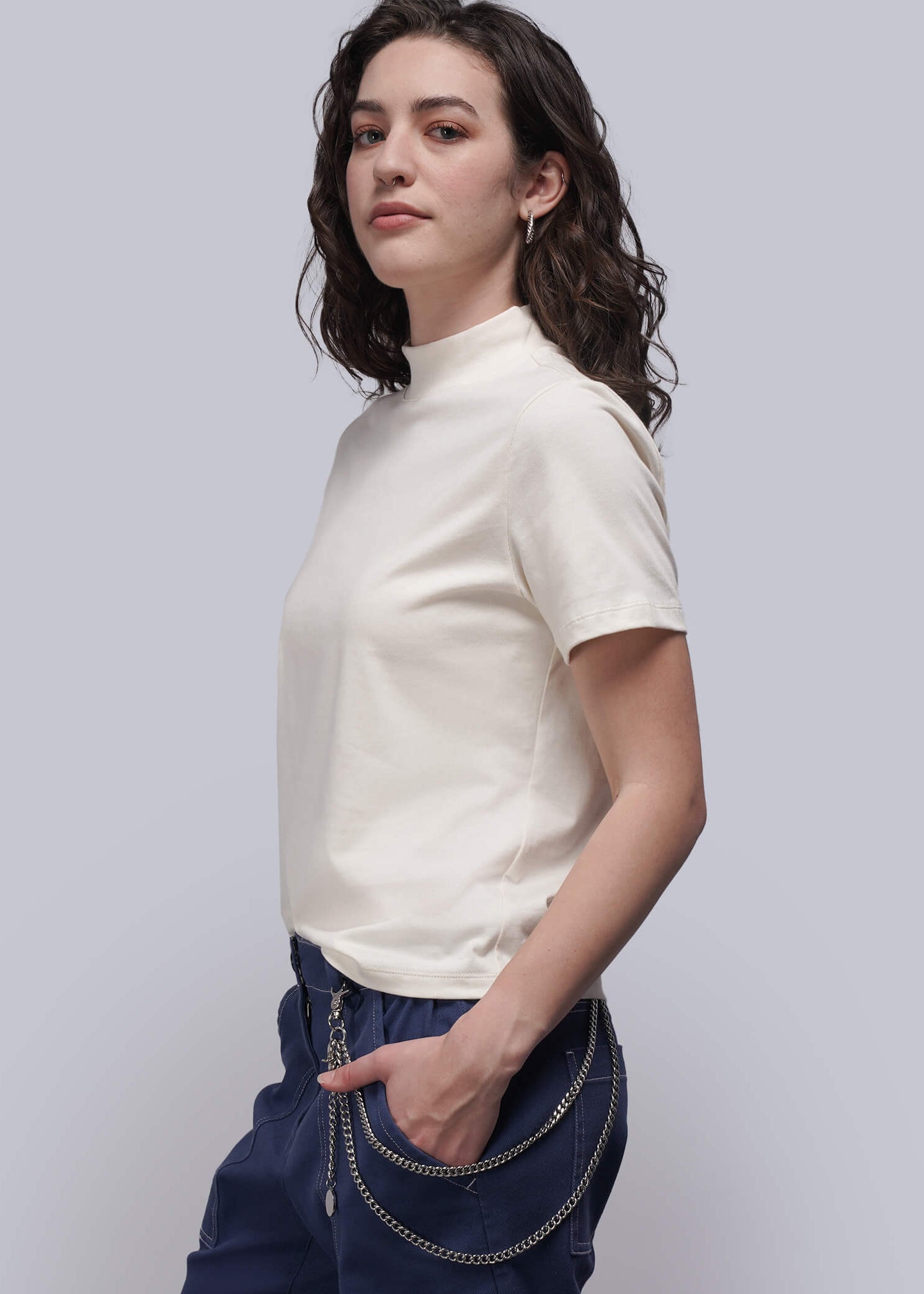 S=Woman wearing a white top and blue pants against a light gray background