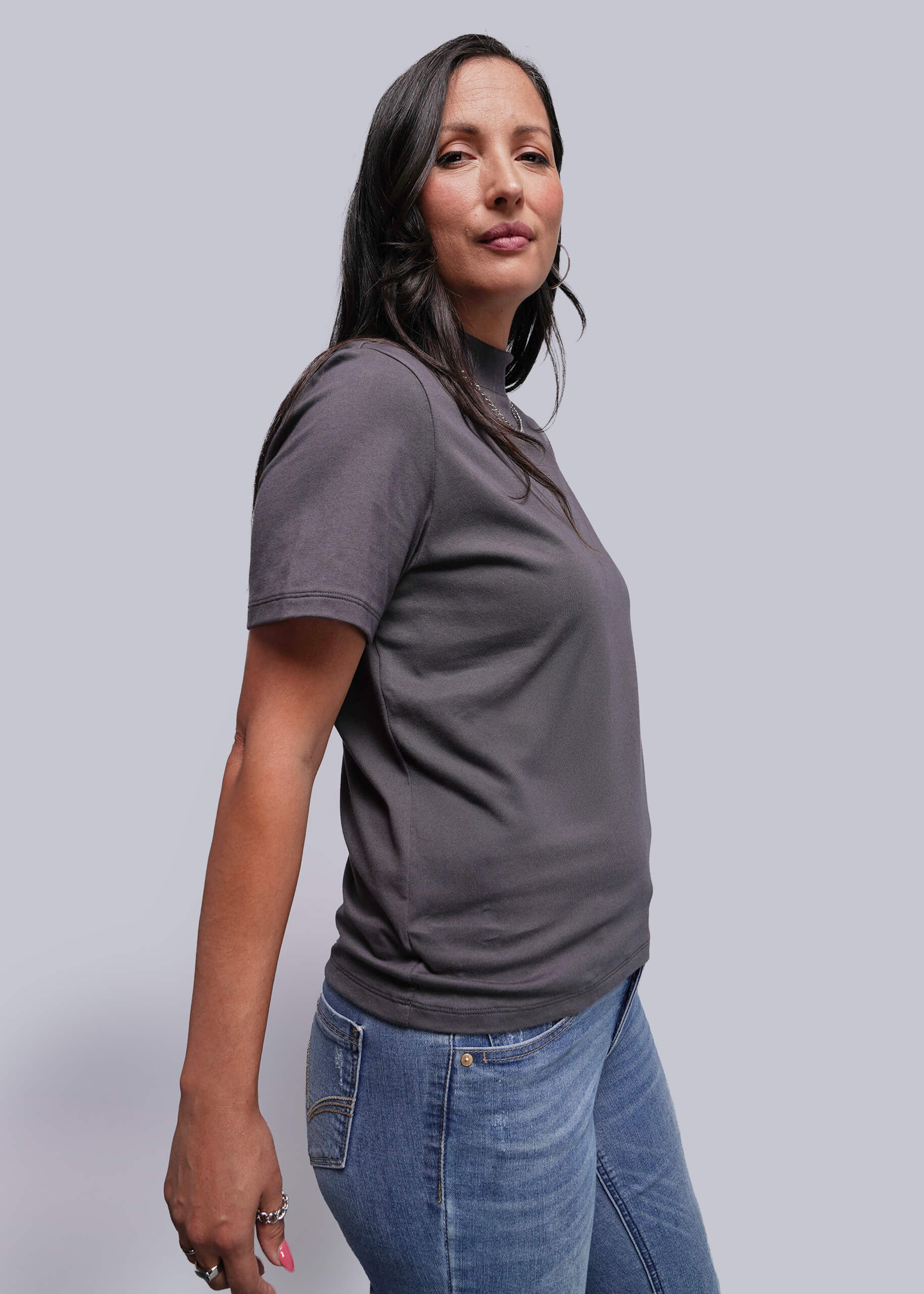 Woman wearing a gray t-shirt and blue jeans against a plain background