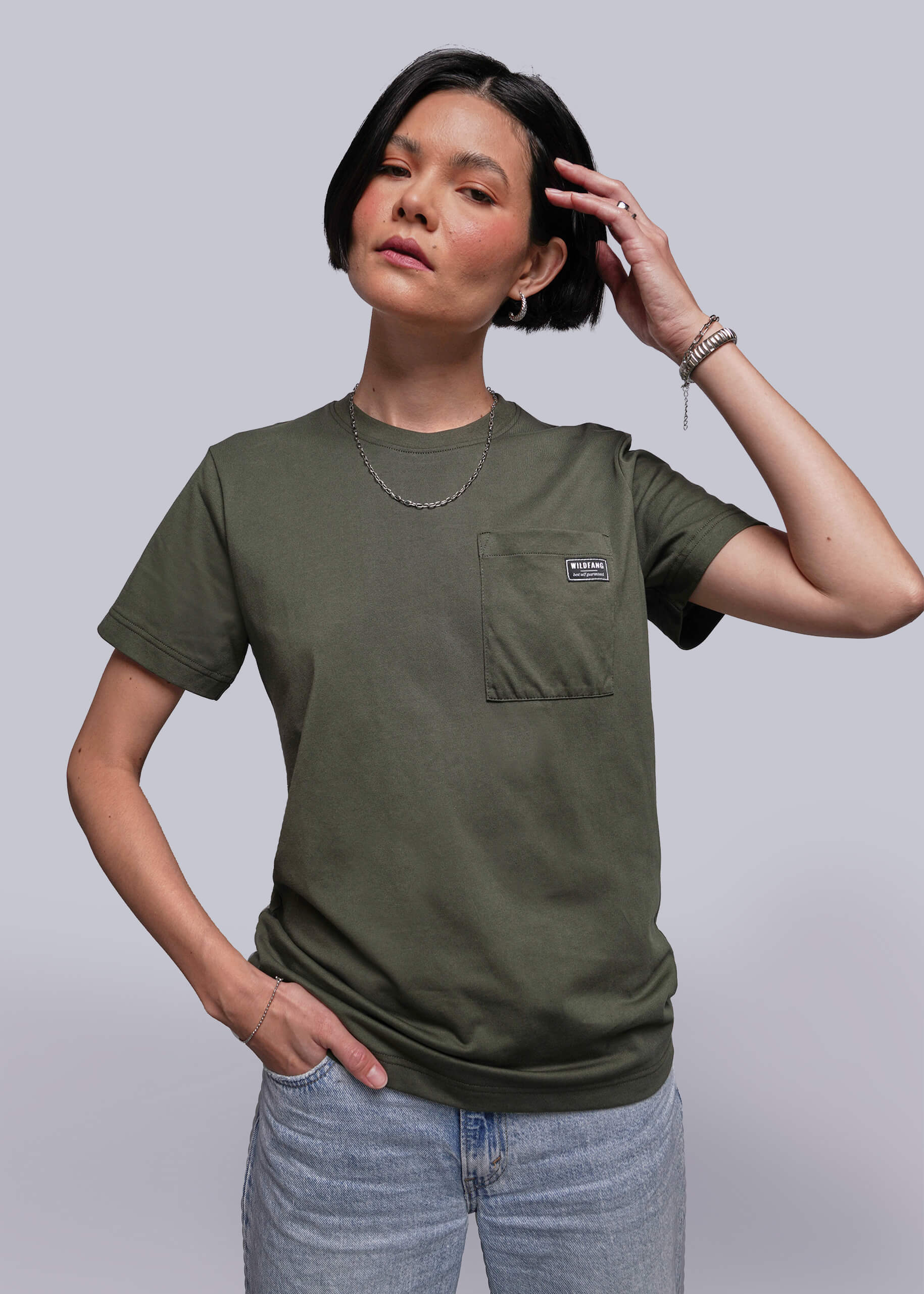 S=Person wearing an olive green t-shirt with a pocket on a plain background