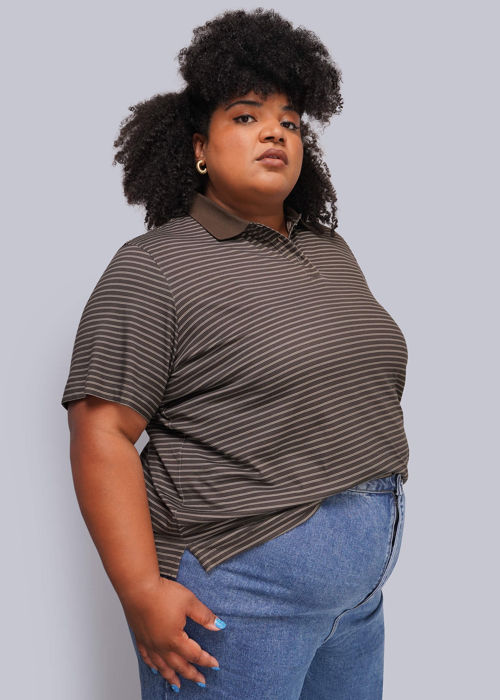 1X=A plus-size model wearing a brown and dark gray striped short-sleeve polo shirt with blue jeans, standing against a solid gray studio background.