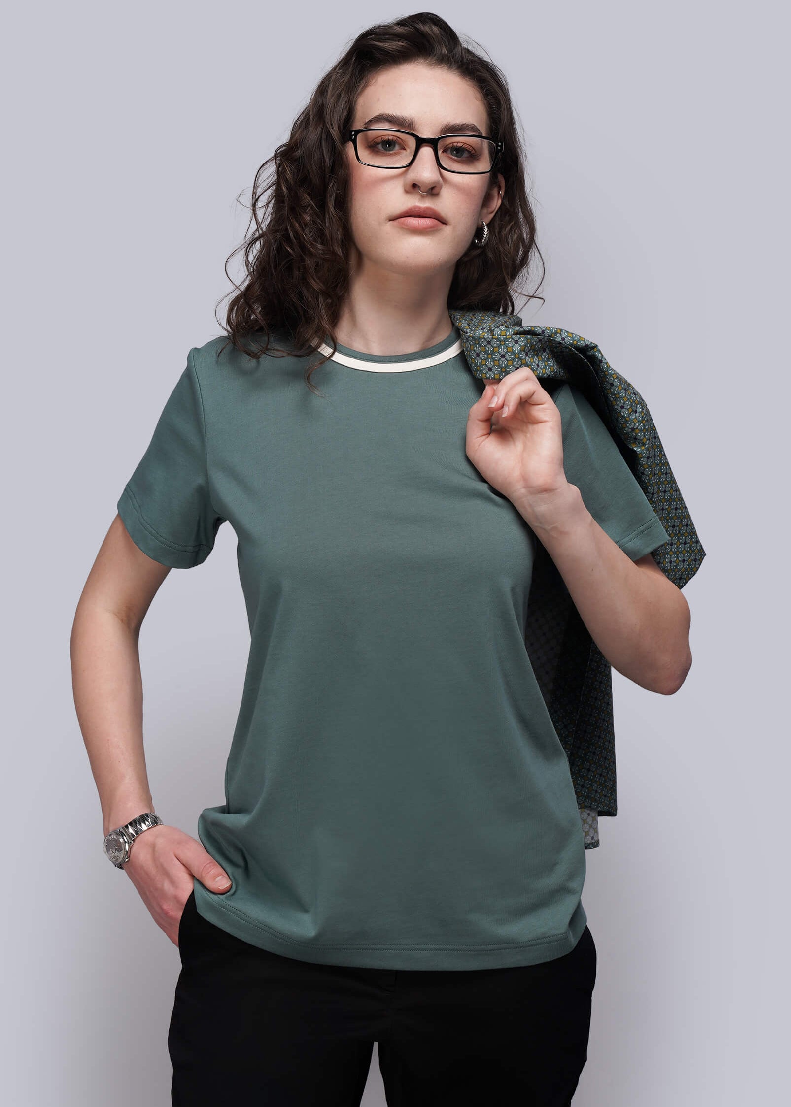 Woman wearing a green t-shirt and black pants against a plain background
