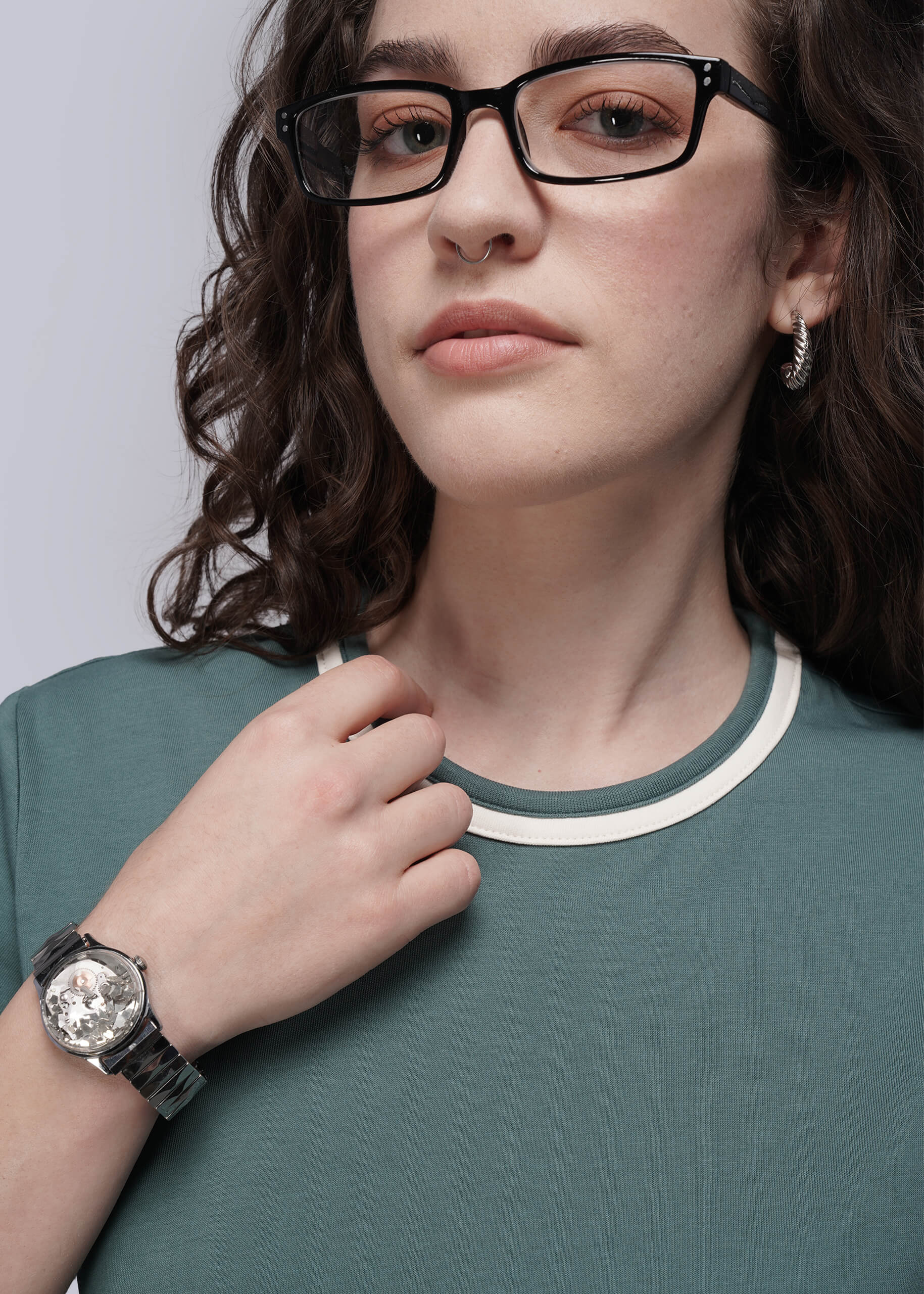 S=Person wearing glasses, a watch, and a teal tee with a neutral background