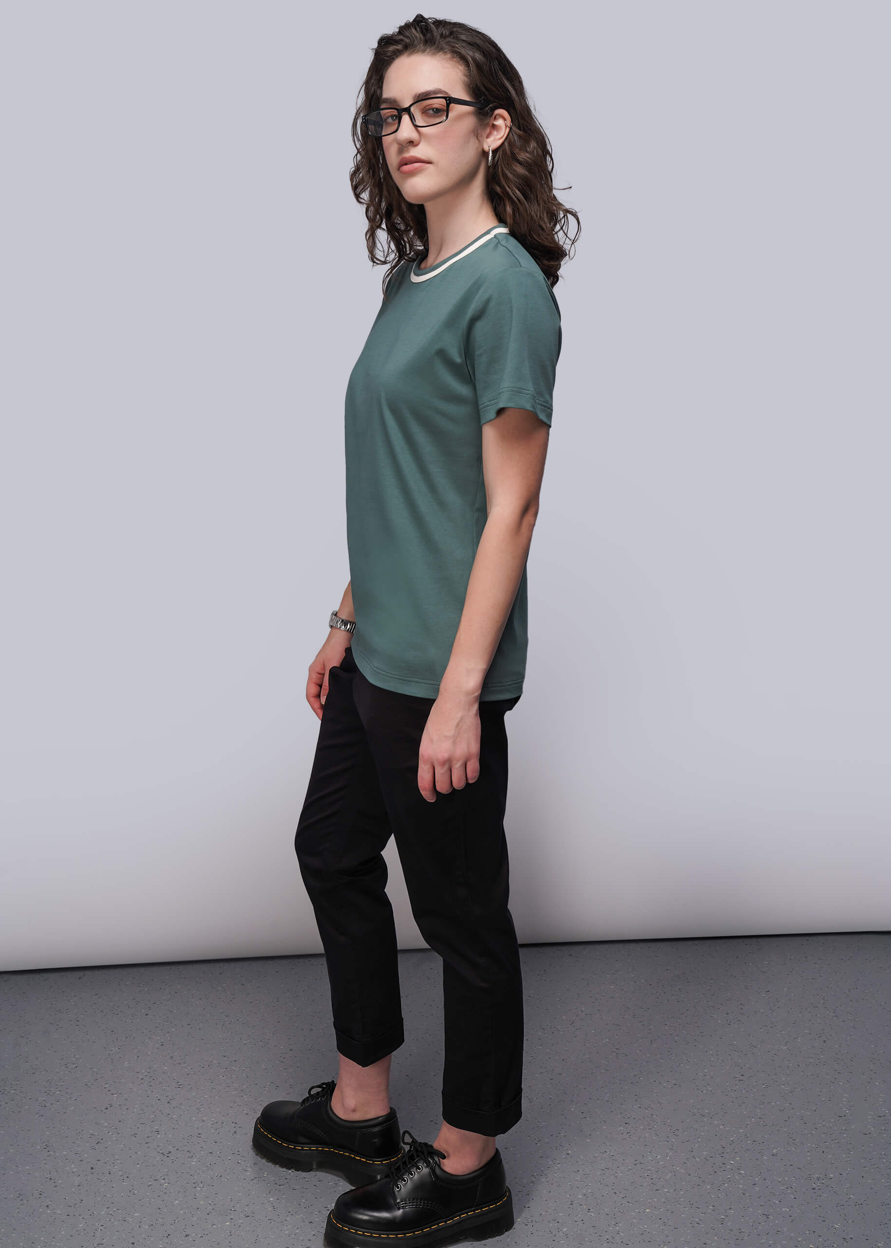 S=Person wearing a green t-shirt and black pants against a plain background