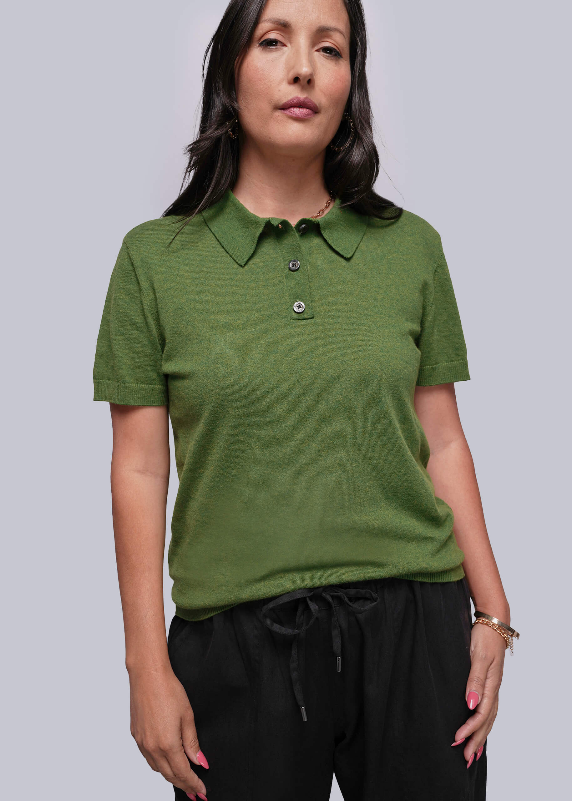Woman wearing a green polo shirt against a plain background