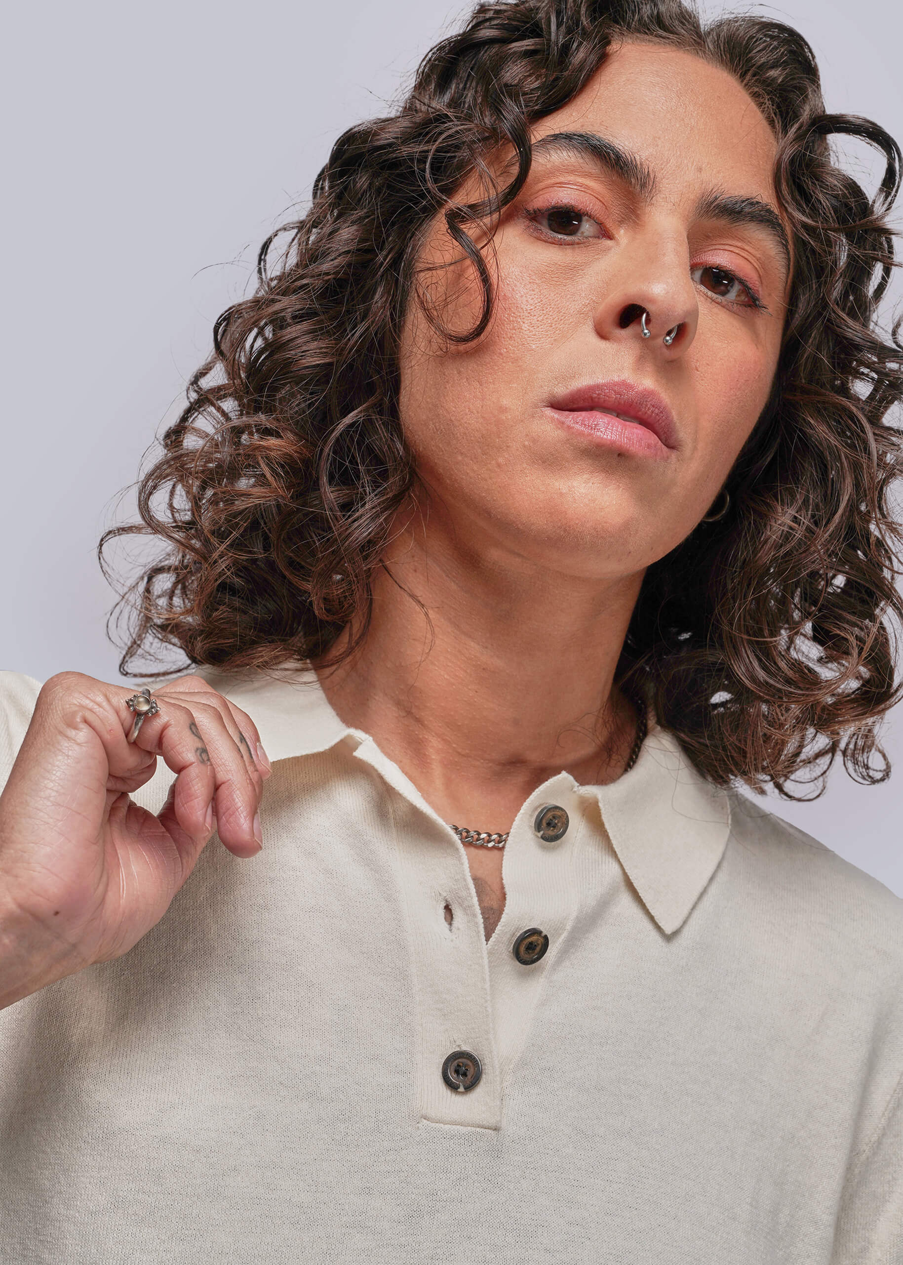 Person wearing a light-colored polo shirt with a neutral background