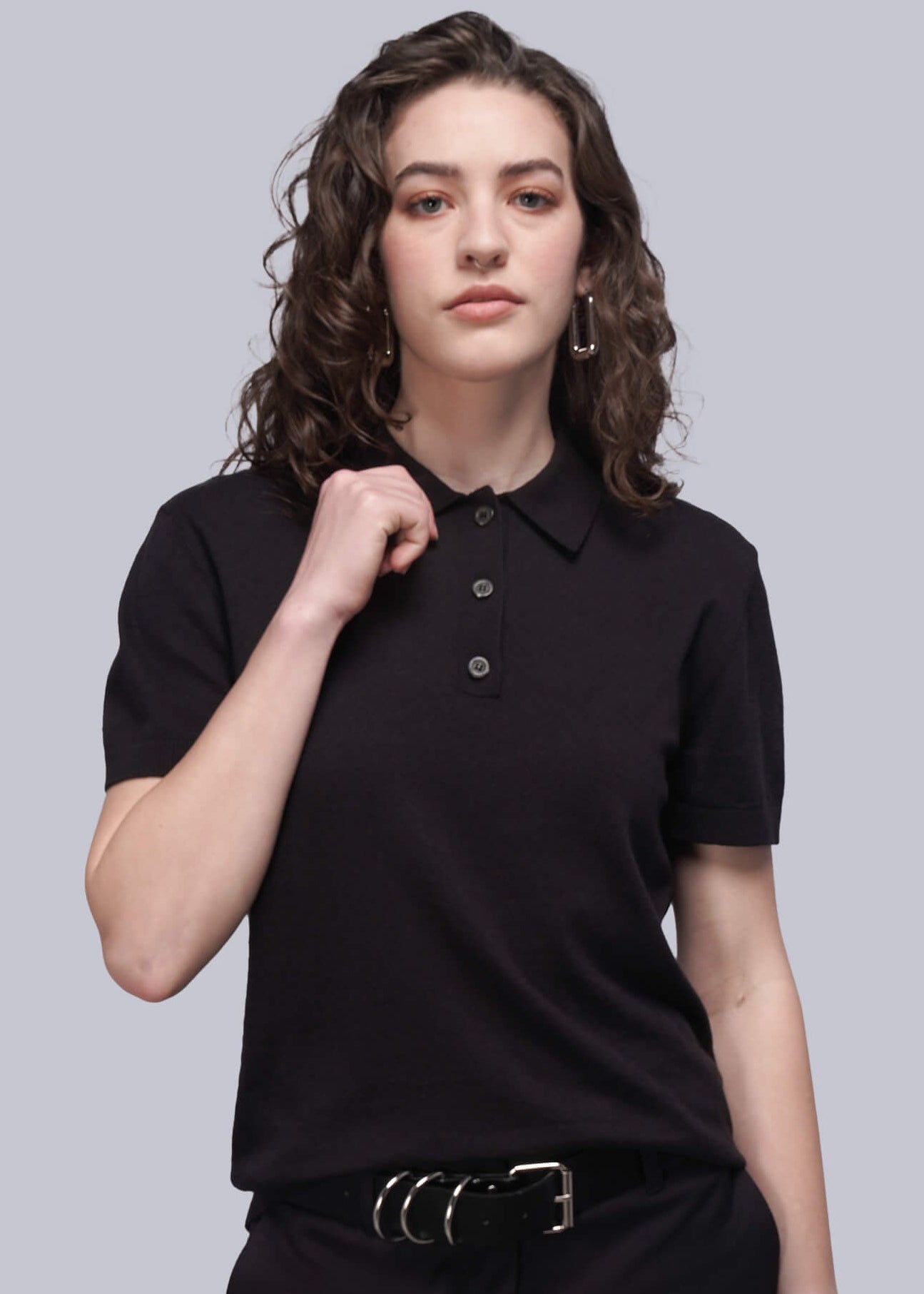 Person wearing a black polo shirt and black pants on a gray background