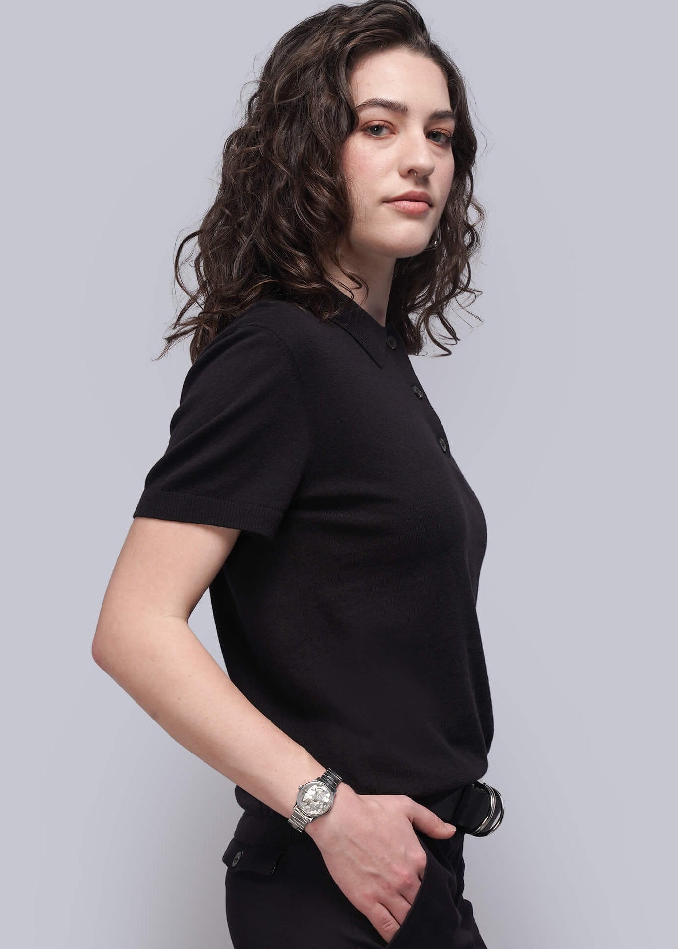 Person wearing a black outfit against a light gray background