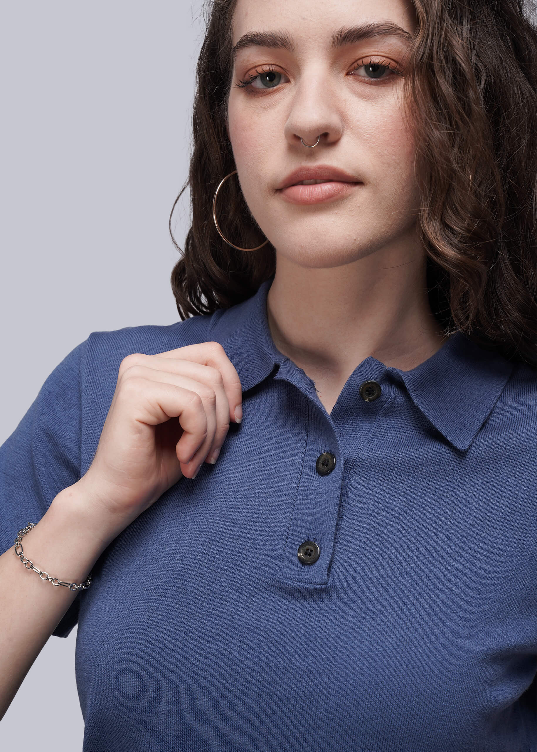 S=Woman wearing a blue polo shirt against a plain background