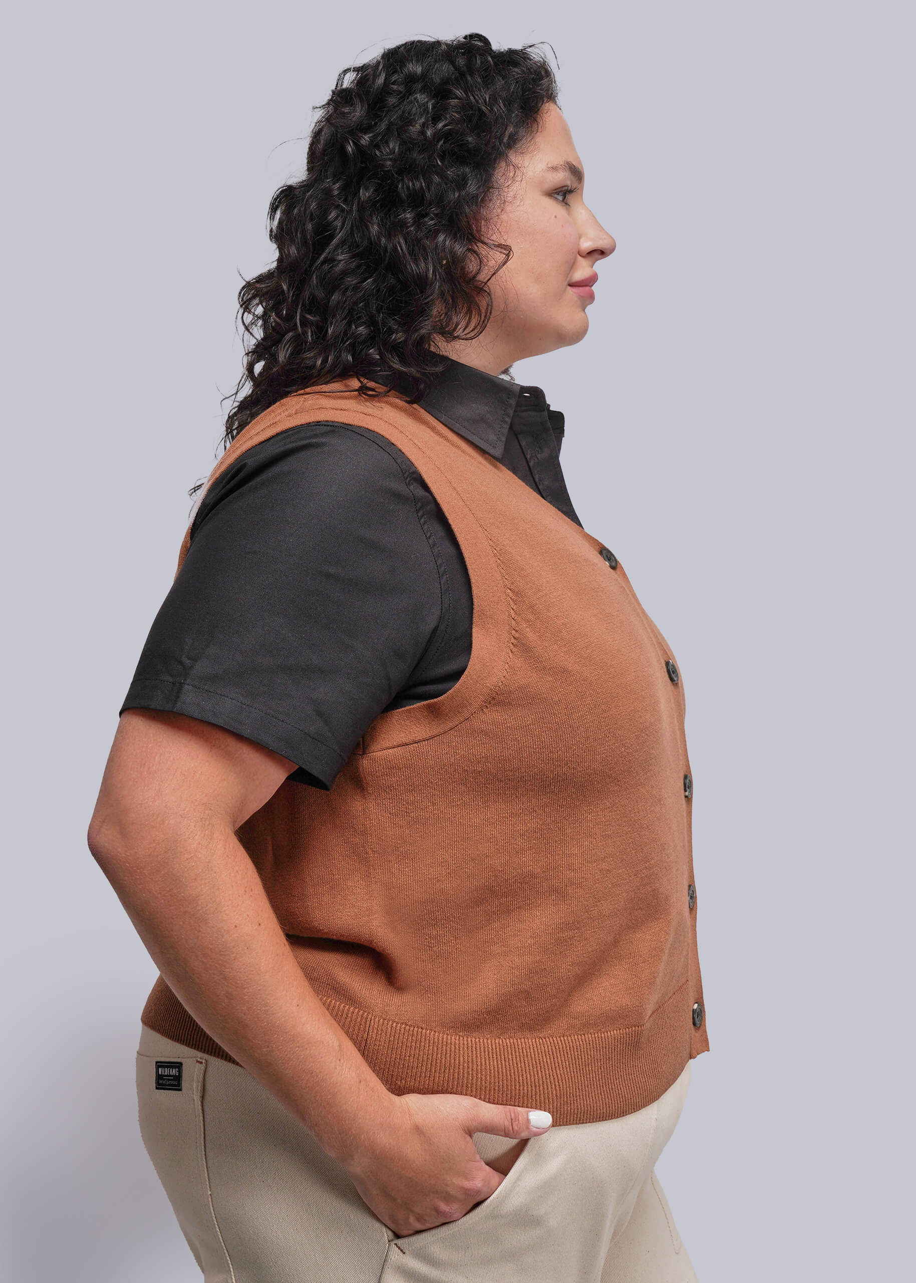 1X=Person wearing a brown vest over a black shirt on a plain background