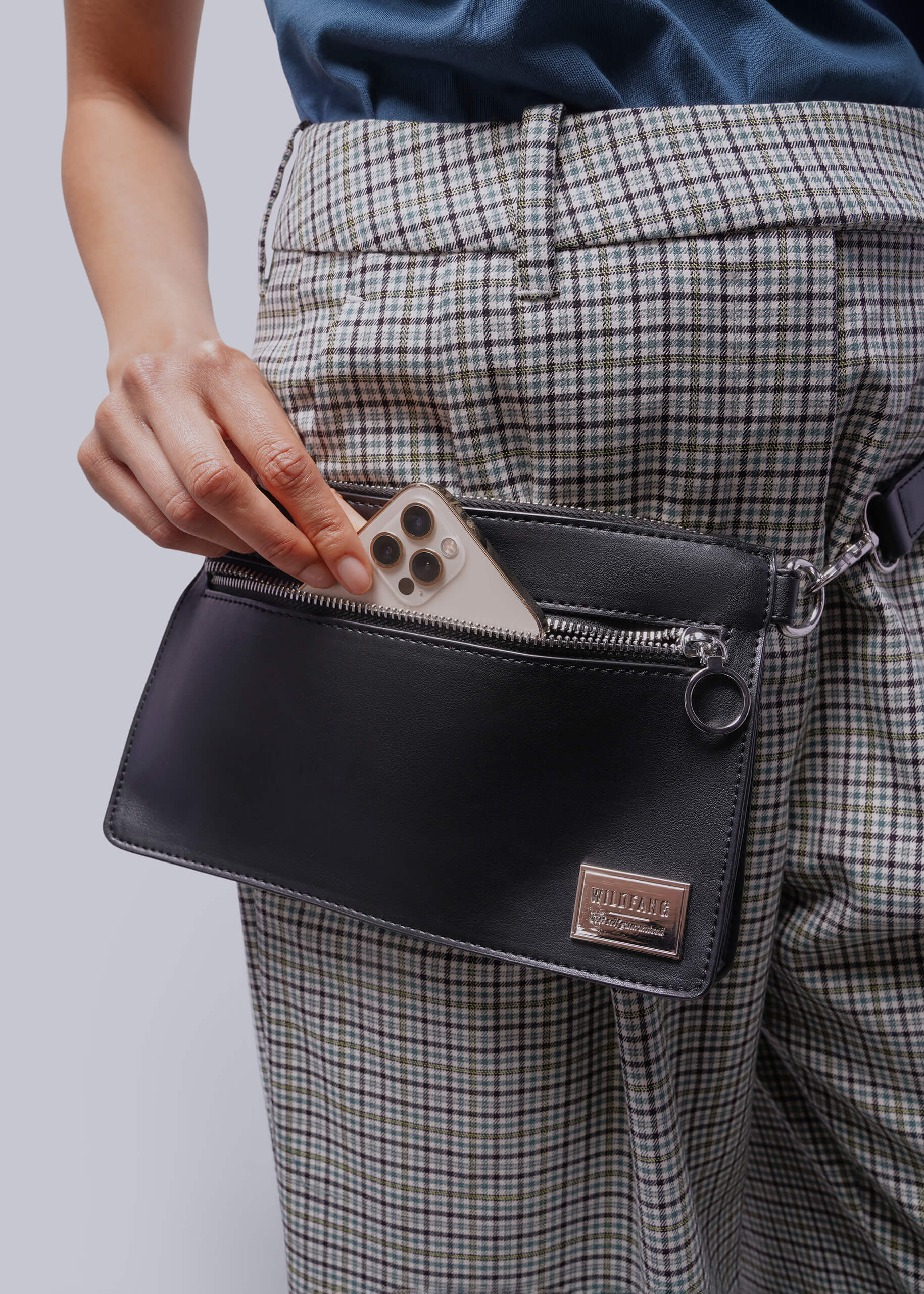 Person wearing plaid pants with a black waist bag with phone in pocket.