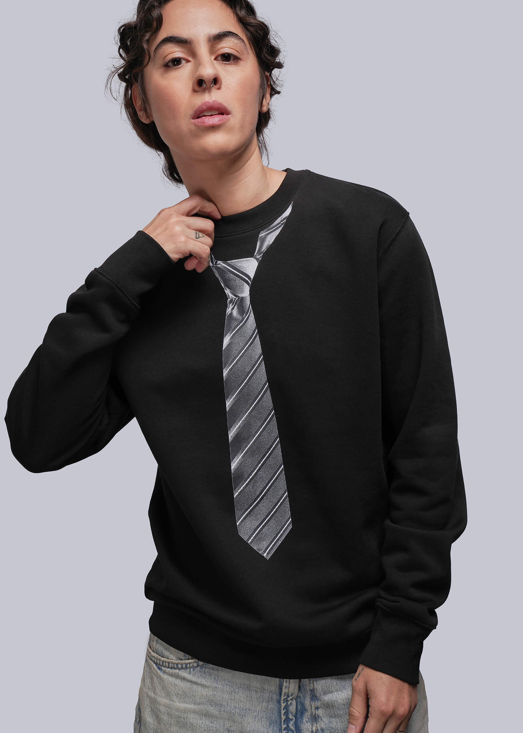 Person wearing a black sweatshirt with a tie design on a plain background